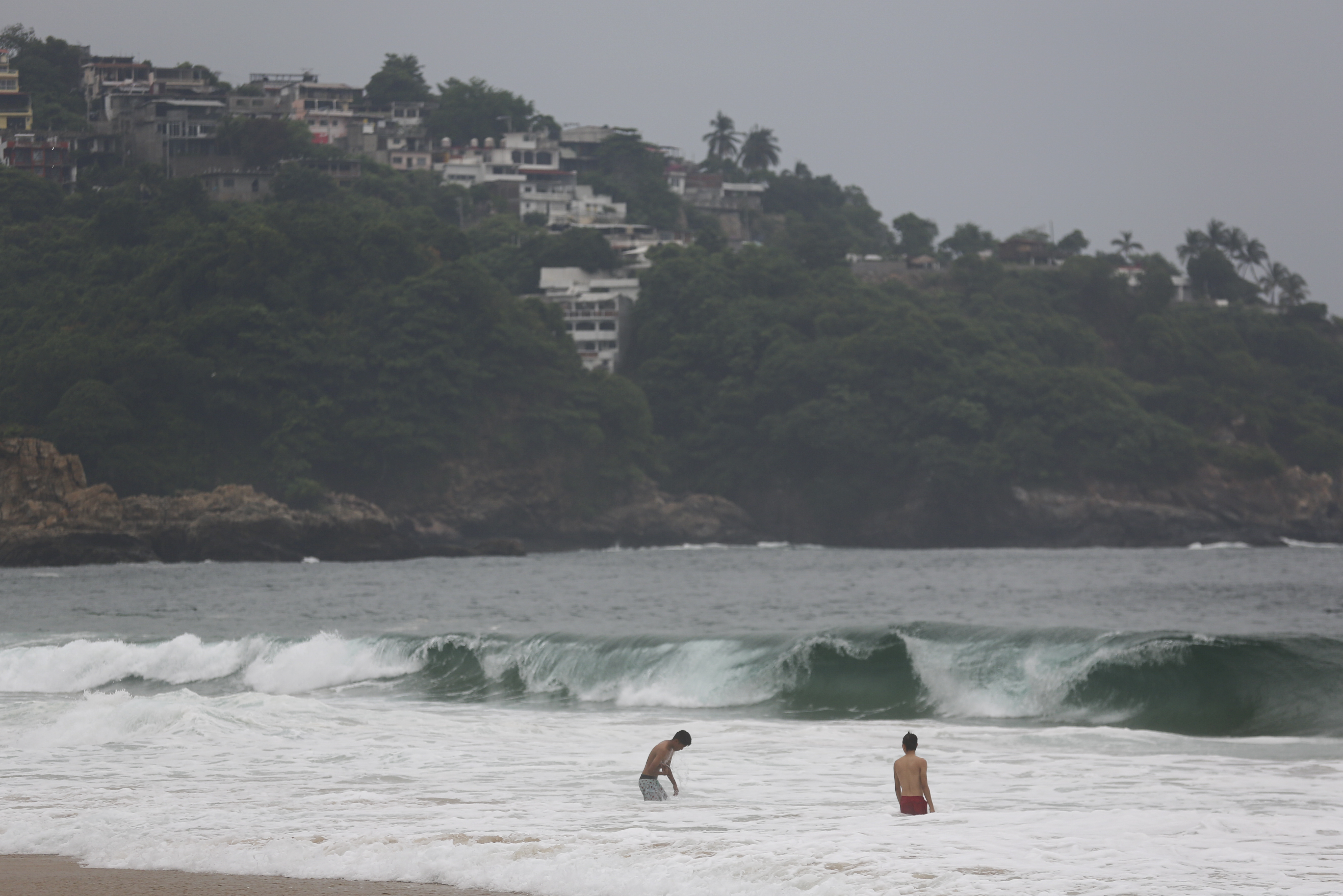 Tourists swim in Acapulco, Mexico, Tuesday. Hurricane Otis ripped through Mexico's southern Pacific coast as a powerful Category 5 storm, tearing through buildings in the resort city of Acapulco.