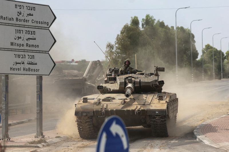 Israeli soldiers drive in a tank by Israel's border with Gaza in southern Israel, Oct. 10. Israel has agreed to delay the invasion of Gaza for now, so the U.S. can rush missile defenses to the region, the Wall Street Journal reported Wednesday.