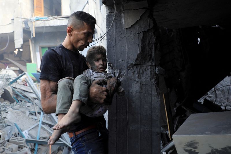 A man carries a child as Palestinians search for casualties at the site of an Israeli strike on a residential building in Gaza City, Wednesday.