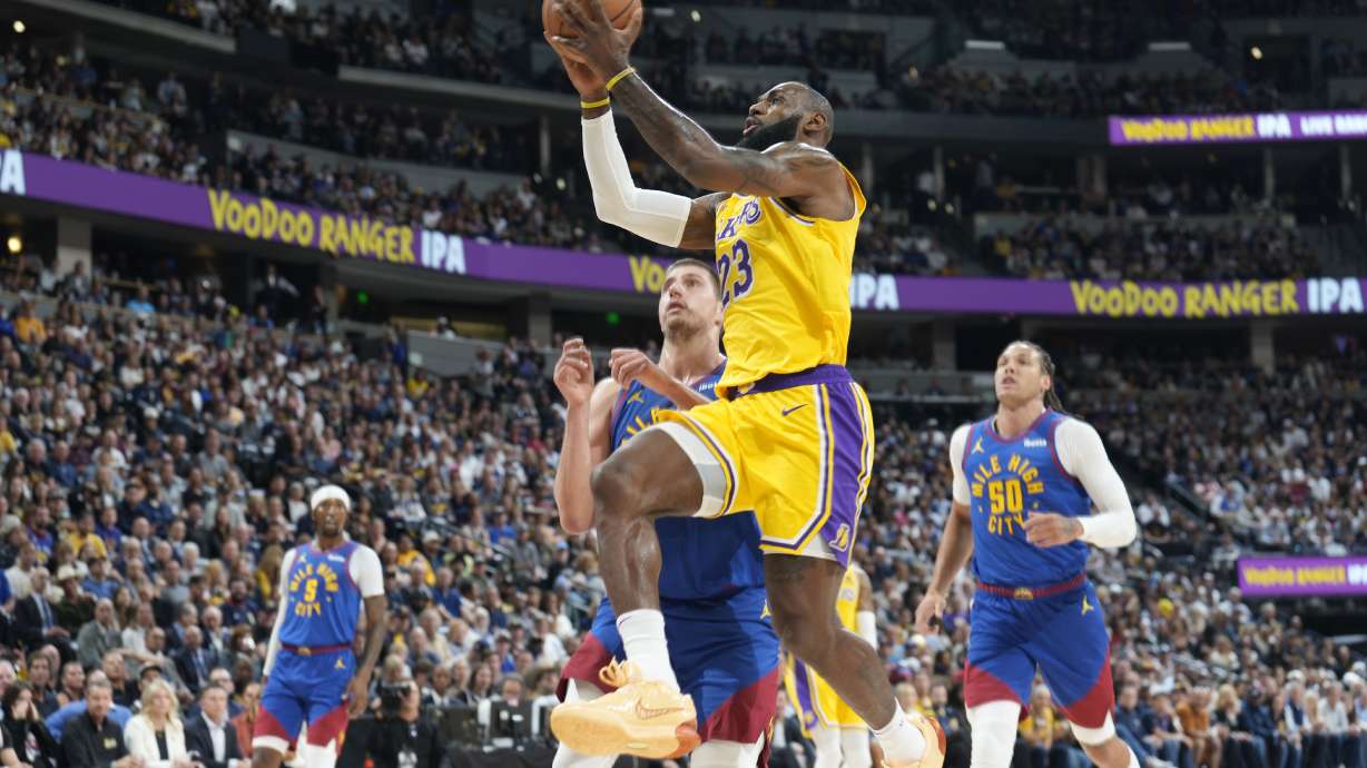 Los Angeles Lakers forward LeBron James drives to the basket past Denver Nuggets center Nikola Jokic and forward Aaron Gordon, right, during the first half of an NBA basketball game Tuesday, Oct. 24, 2023, in Denver.