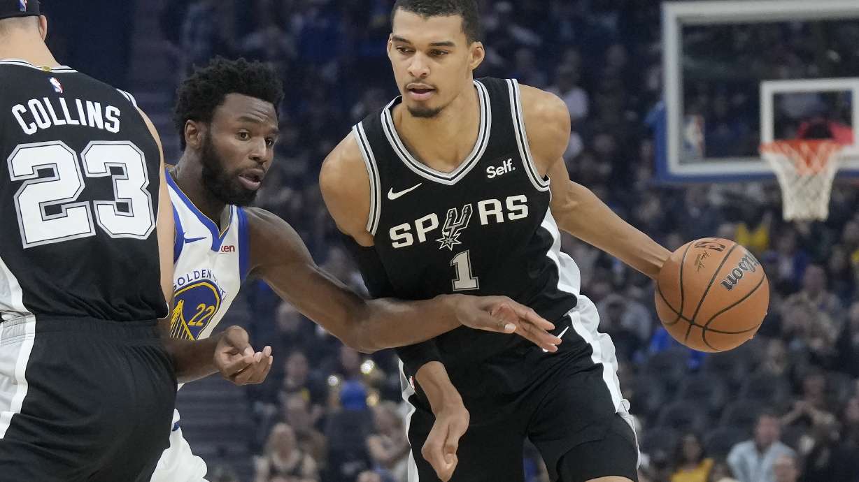 San Antonio Spurs center Victor Wembanyama (1) drives to the basket against Golden State Warriors forward Andrew Wiggins during the first half of an NBA preseason basketball game in San Francisco, Friday, Oct. 20, 2023.
