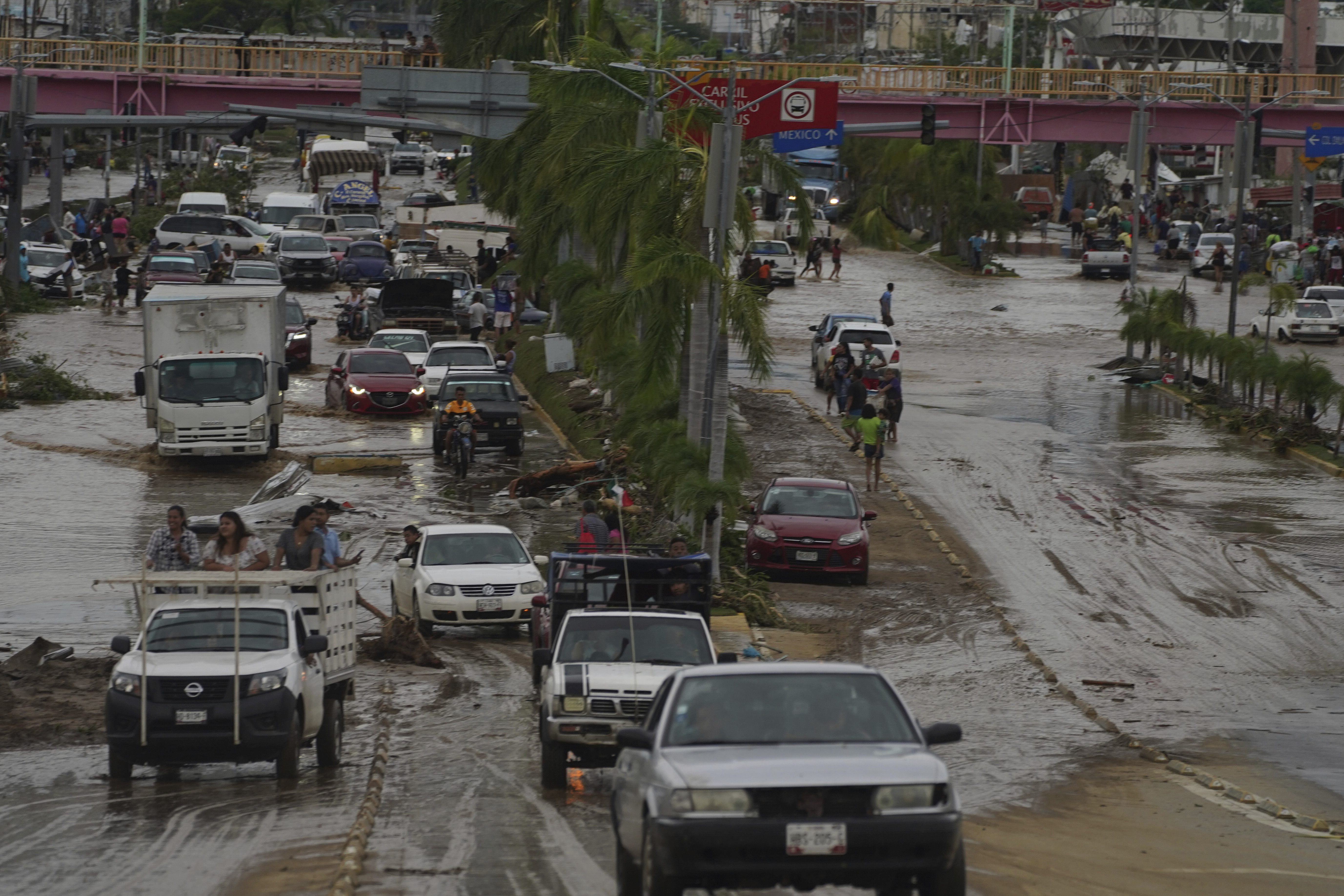 Cars cross a flood-damaged avenue after Hurricane Otis ripped through Acapulco, Mexico, Wednesday.