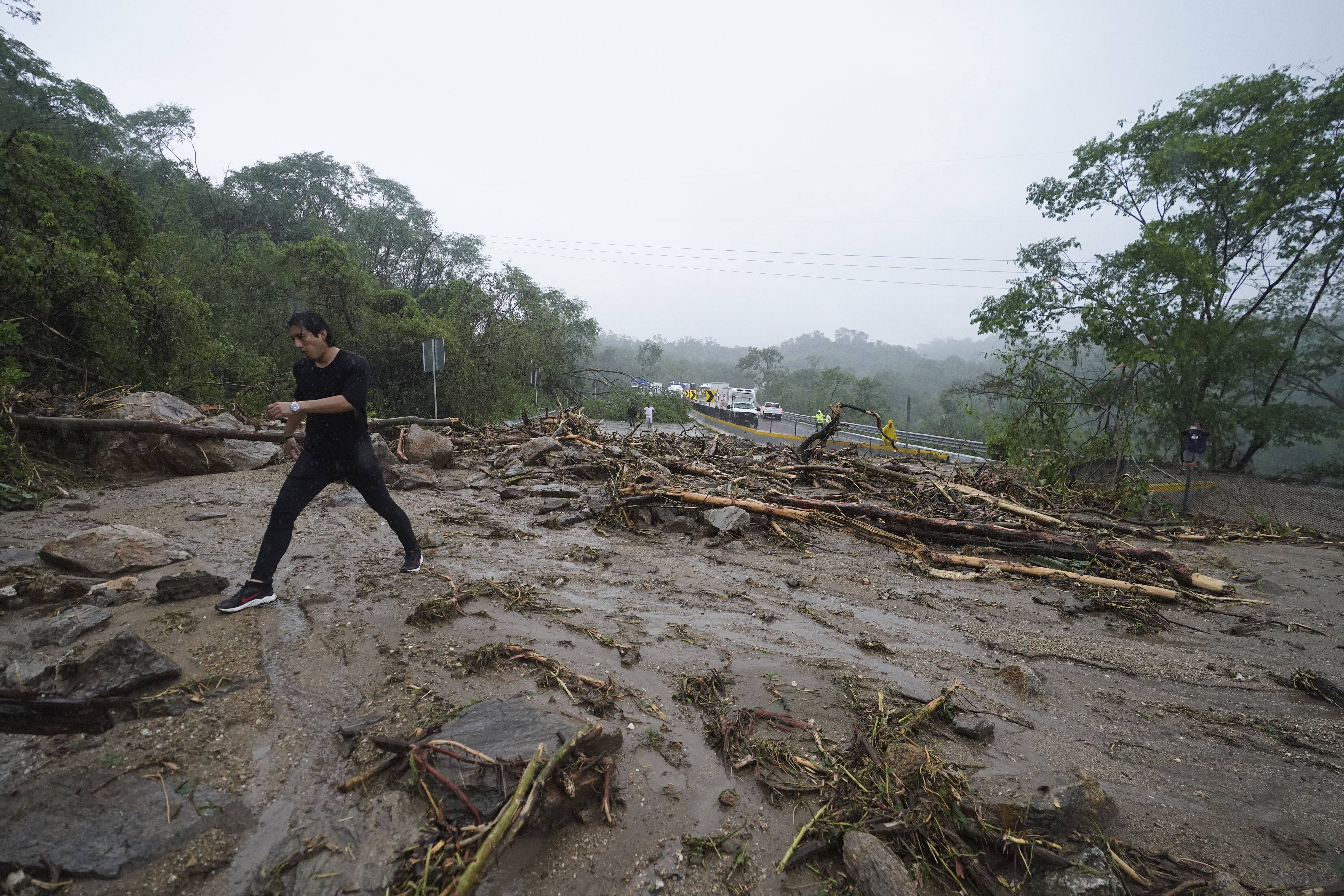 A man crosses a highway blocked by a landslide triggered by Hurricane Otis near Acapulco, Mexico, Wednesday.