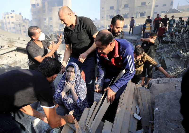 A Palestinian woman is assisted, as people search for casualties at the site of an Israeli strike on a residential building in Gaza City, Wednesday.