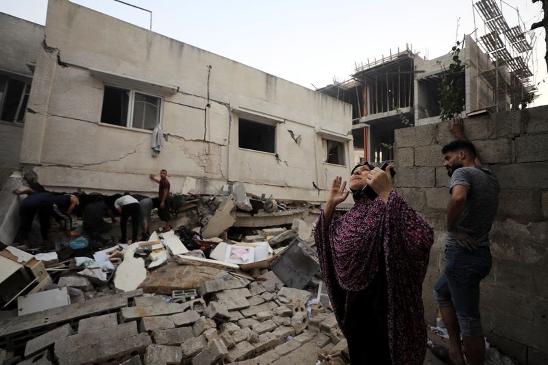 A Palestinian woman gestures as rescue works are conducted, at the site of an Israeli strike on a residential building in Gaza City, Wednesday.