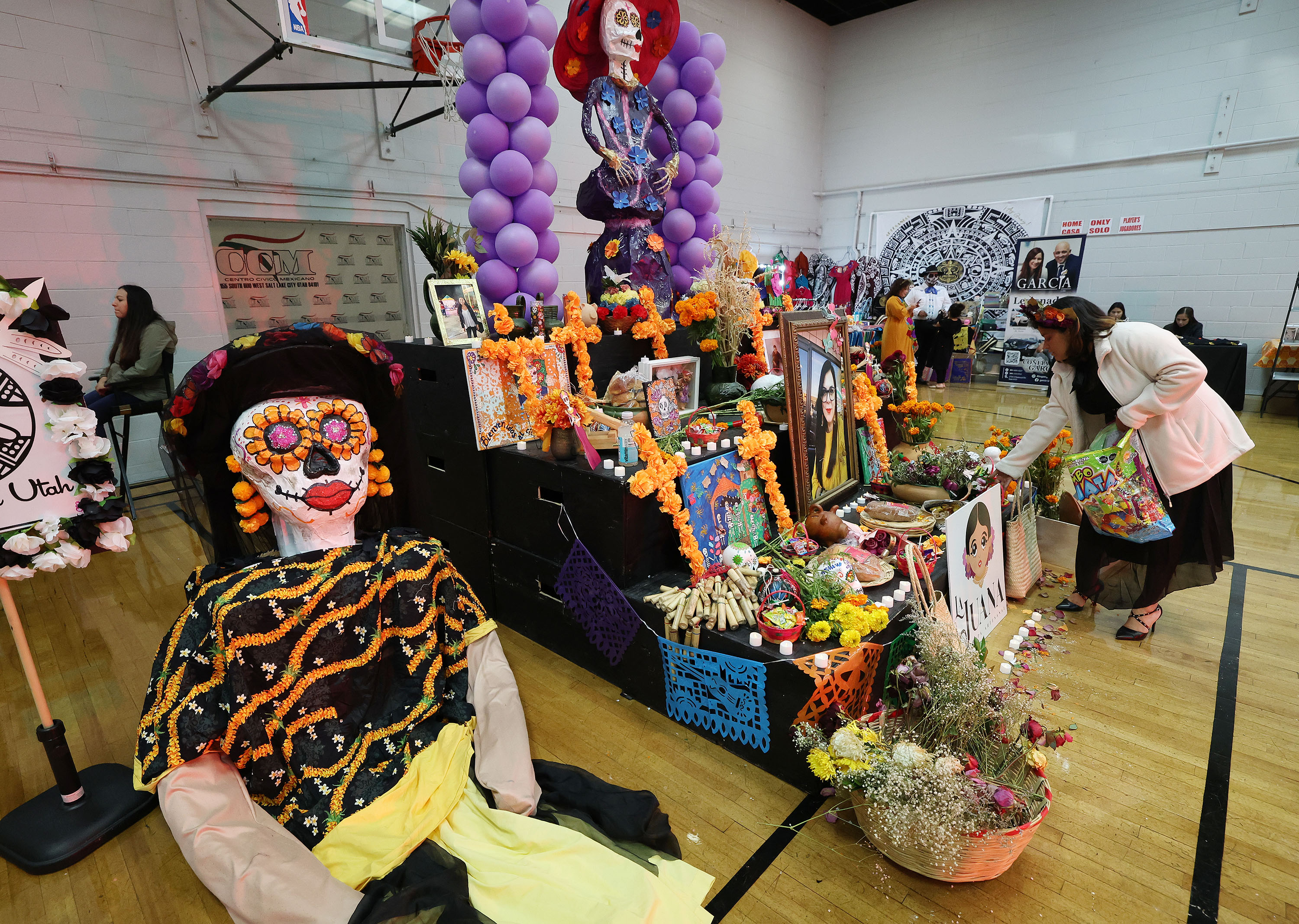 An attendee puts candy on an altar in remembrance of Gaby Ramos and other victims of domestic violence at Centro Civico Mexicano in Salt Lake City on Thursday.