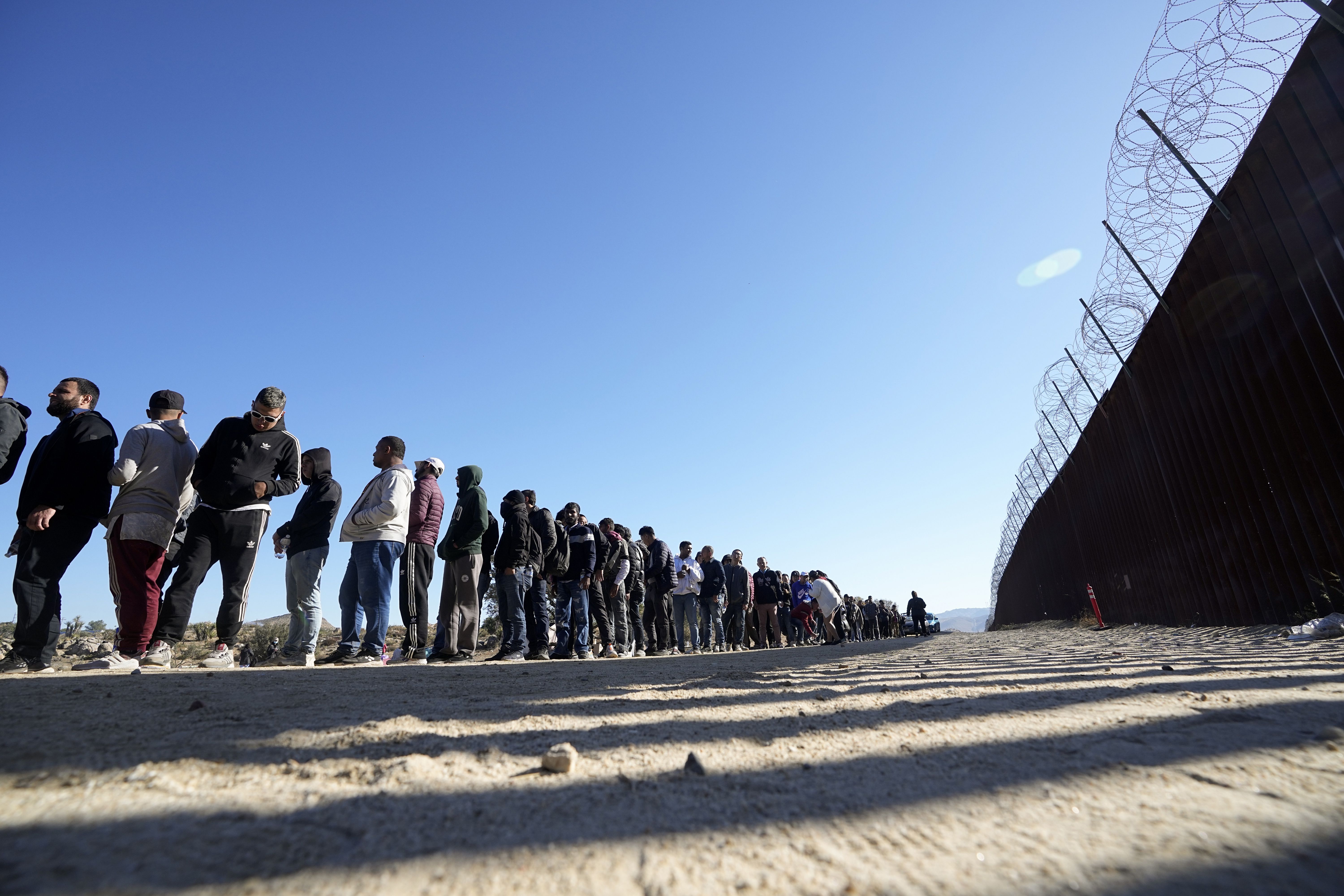 Men line up to receive food from volunteers with Border Kindness after crossing the U.S. border with Mexico on Tuesday near Jacumba, California. Standing at the U.S.-Mexico border Friday with other Republican senators, Utah Sen. Mike Lee said he had a message for anyone thinking of crossing the border illegally.
