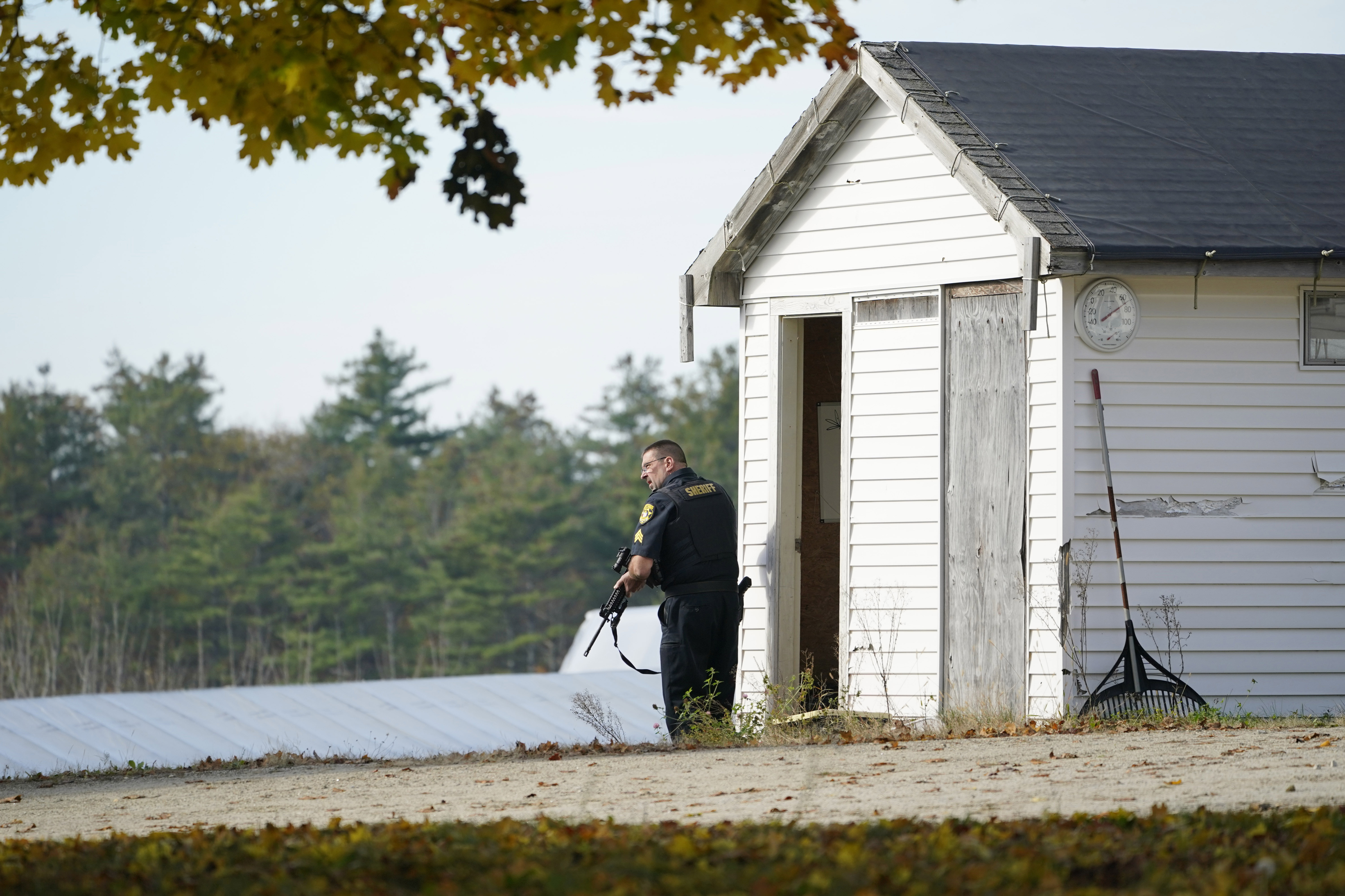 A police officer keeps watch during a manhunt at a farm for the suspect in this week's deadly mass shootings, Friday, in Lisbon, Maine. Police are still searching for the man who killed at least 18 in separate shootings at a bowling alley and restaurant in Lewiston on Wednesday.