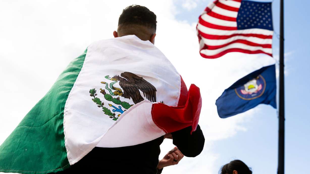 The American flag waves above an attendee wrapped in the Mexican flag at the "I Stand with All Immigrants Rally" in front of the Utah Capitol in Salt Lake City on Saturday.