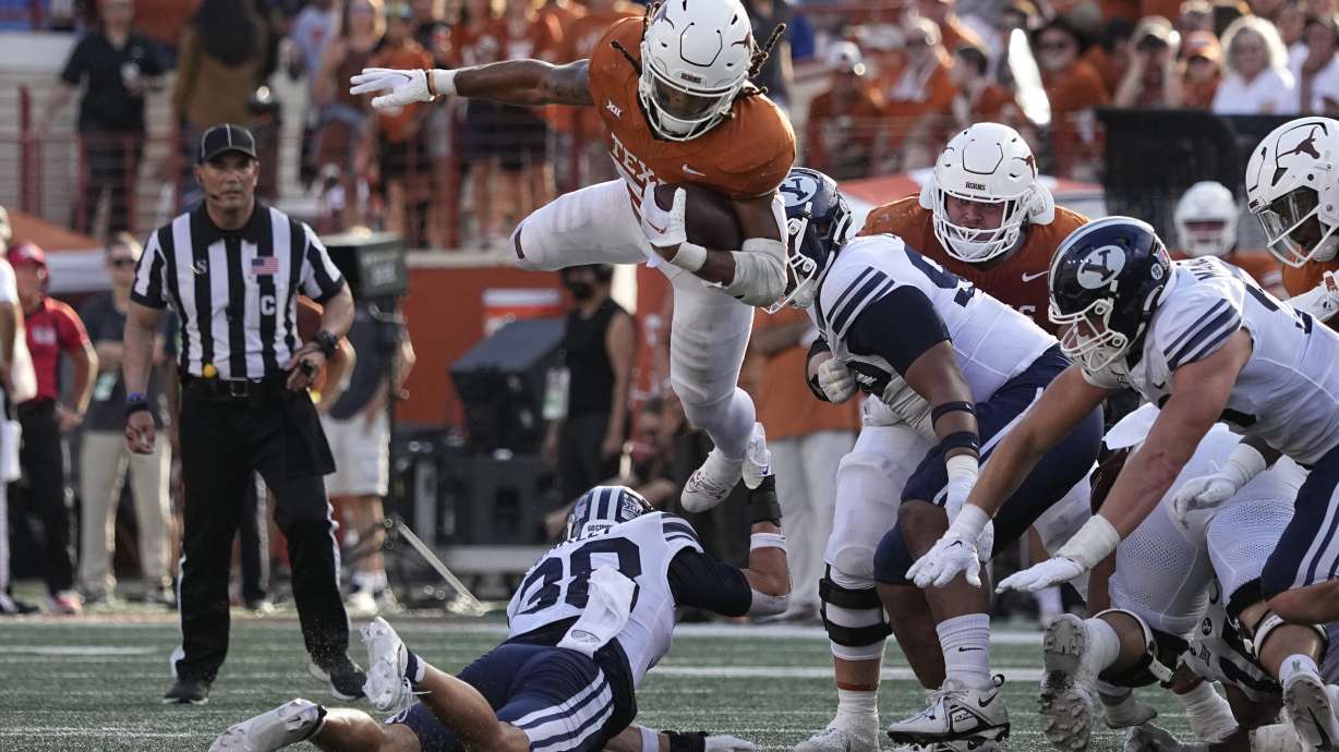 Texas running back Jonathon Brooks (24) is upended by BYU safety Crew Wakley (38) on a run during the second half of an NCAA college football game in Austin, Texas, Saturday, Oct. 28, 2023.