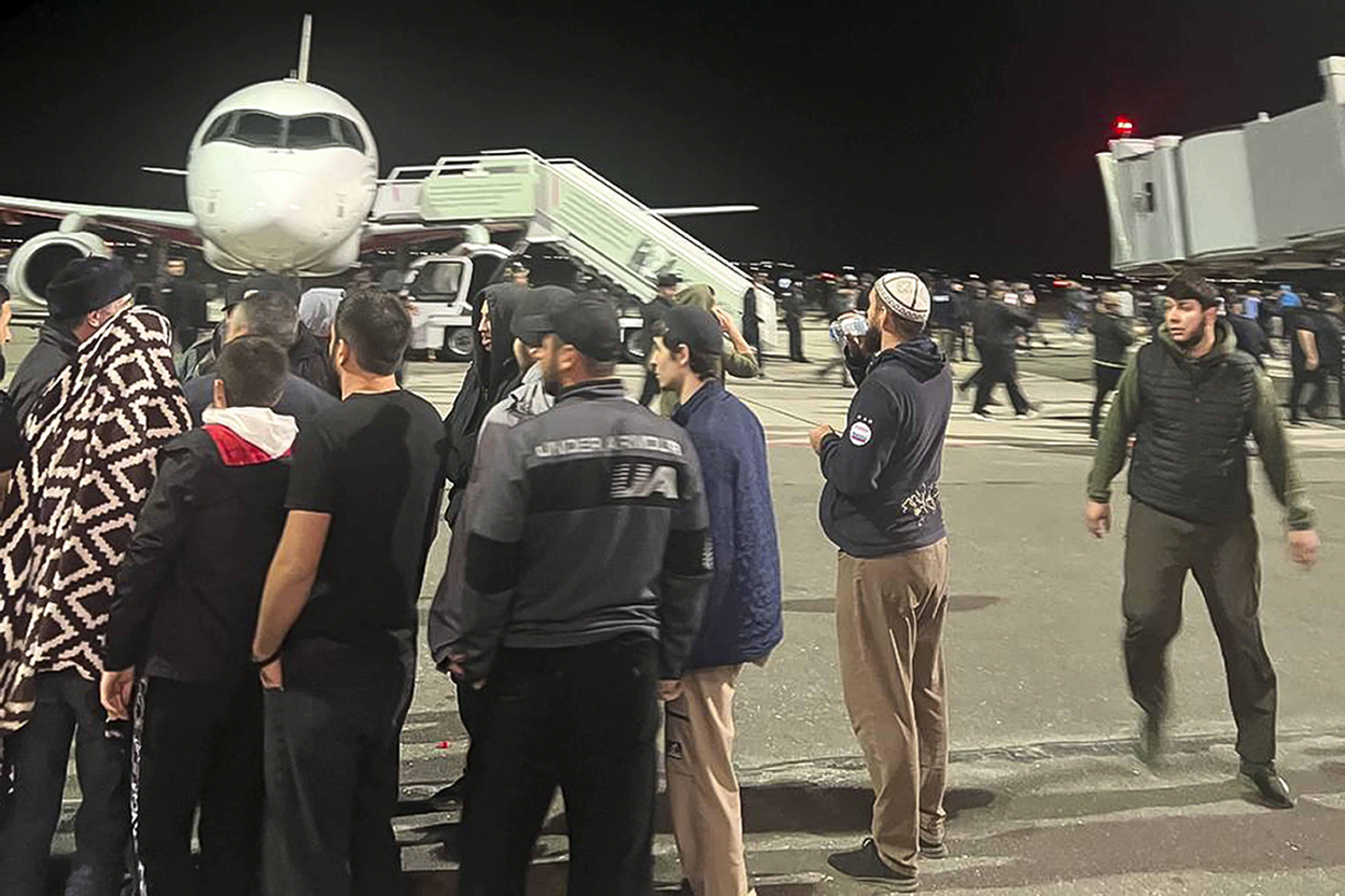 People in the crowd shout antisemitic slogans at an airfield of the airport in Makhachkala, Russia, Monday. Russian news agencies and social media say hundreds of people stormed into the main airport in the Dagestan region.