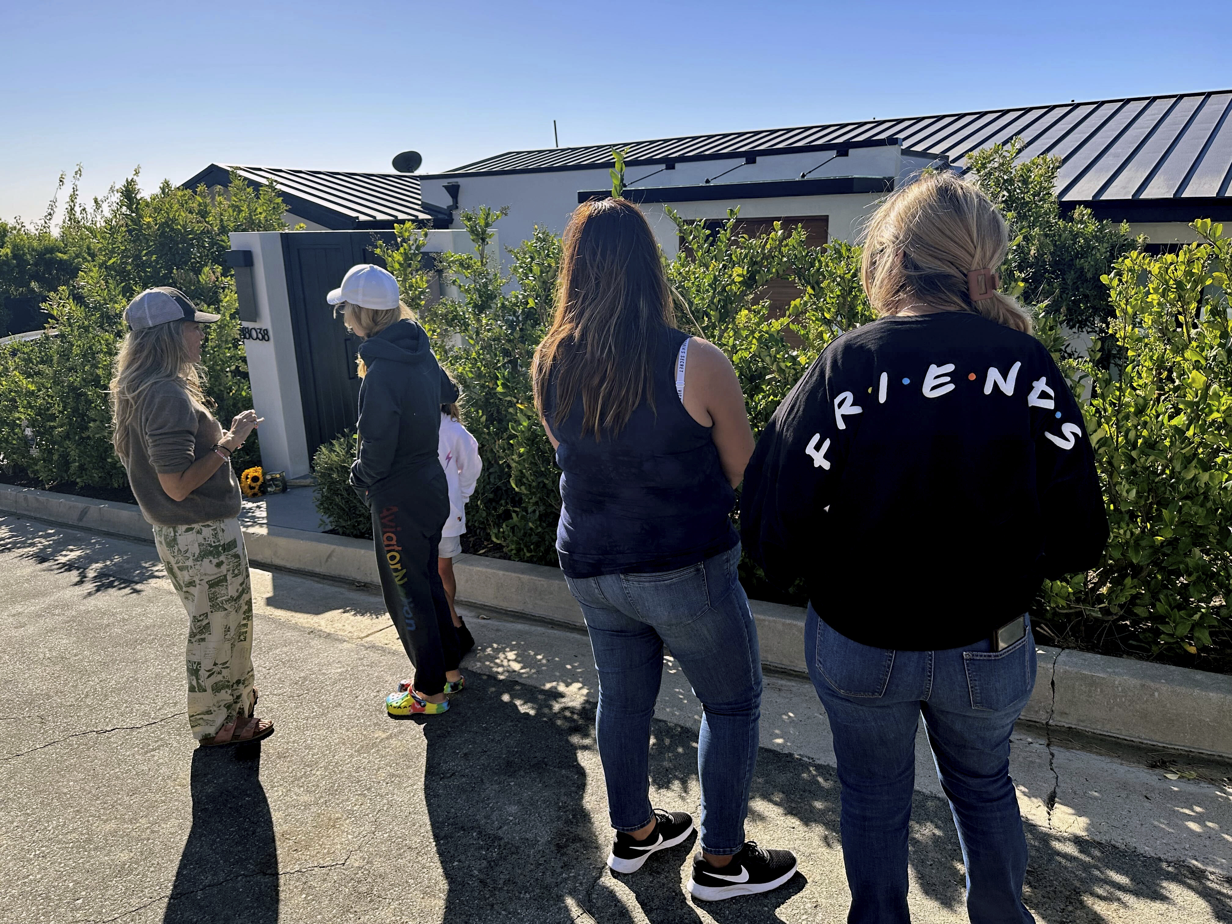 Mourners stand outside the home of actor Matthew Perry, Sunday, Oct. 29, 2023, in the Pacific Palisades area of Los Angeles. Perry, who starred as Chandler Bing in the hit series "Friends," has died. He was 54.