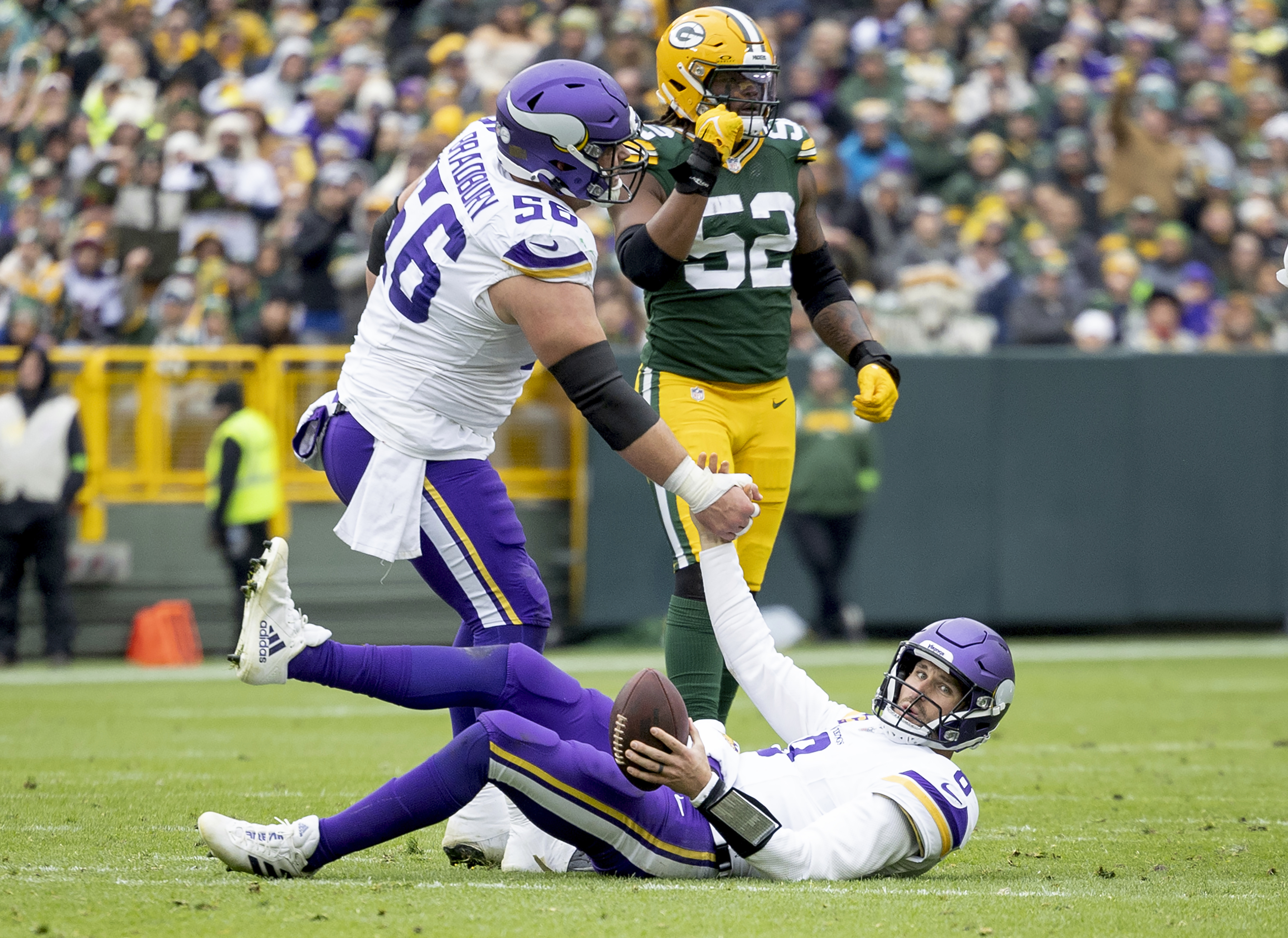 CORRECTS BYLINE TO CARLOS GONZALEZ/STAR TRIBUNE - - Minnesota Vikings quarterback Kirk Cousins (8) is helped up by teammate Garrett Bradbury (56) after a sack in the fourth quarter of an NFL football game against the Green Bay Packers in Miami Gardens, Fla., Sunday, Oct. 29, 2023. 