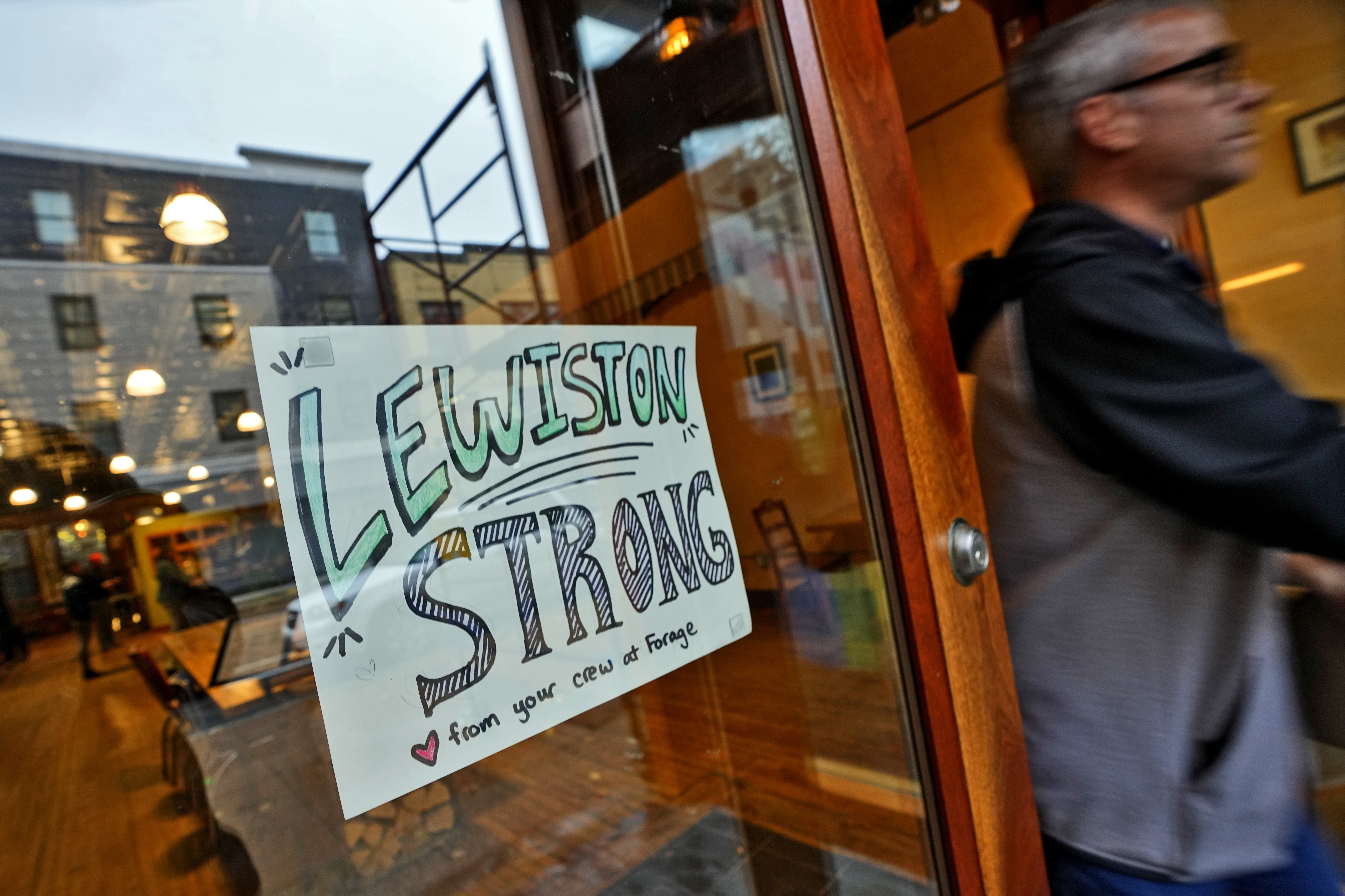 A customer exits a coffee shop, Monday, in Lewiston, Maine. Residents of Lewiston returned to work Monday, the morning after coming together to mourn those lost in Maine's worst mass shooting.
