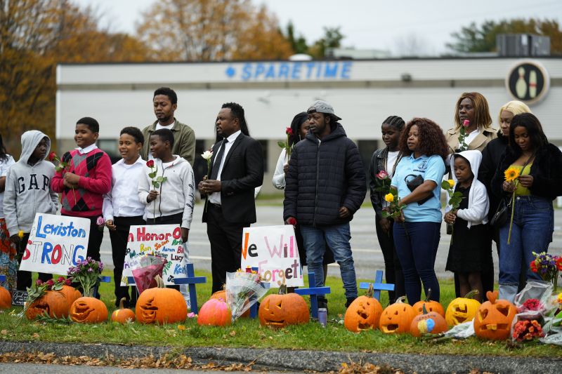 Members of the New Apostolic Church sing and pray at a makeshift memorial outside a bowling alley, the site of one of this week's mass shootings, Sunday in Lewiston, Maine. A gunman killed multiple people at the bowling alley and a bar in Lewiston on Oct. 25.
