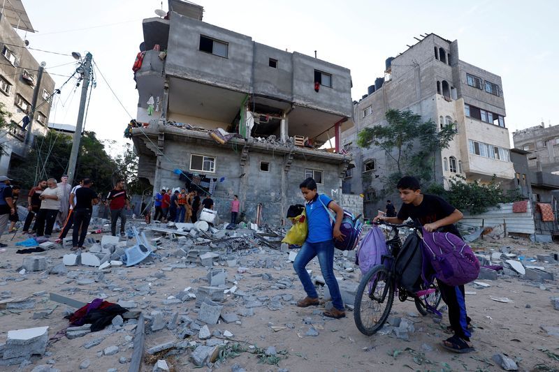 Young Palestinians walk in front of a damaged house in the aftermath of Israeli strikes in Khan Younis in the southern Gaza Strip, Monday.