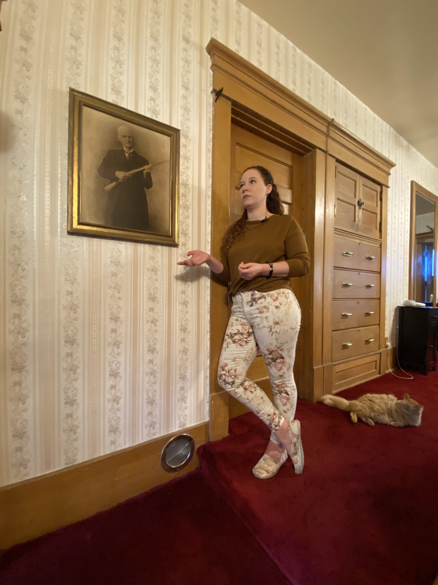 Jackie Loveland stands next to a photo of John M. Browning. Loveland and her husband live in the historic Browning Mansion and feel it may be haunted.