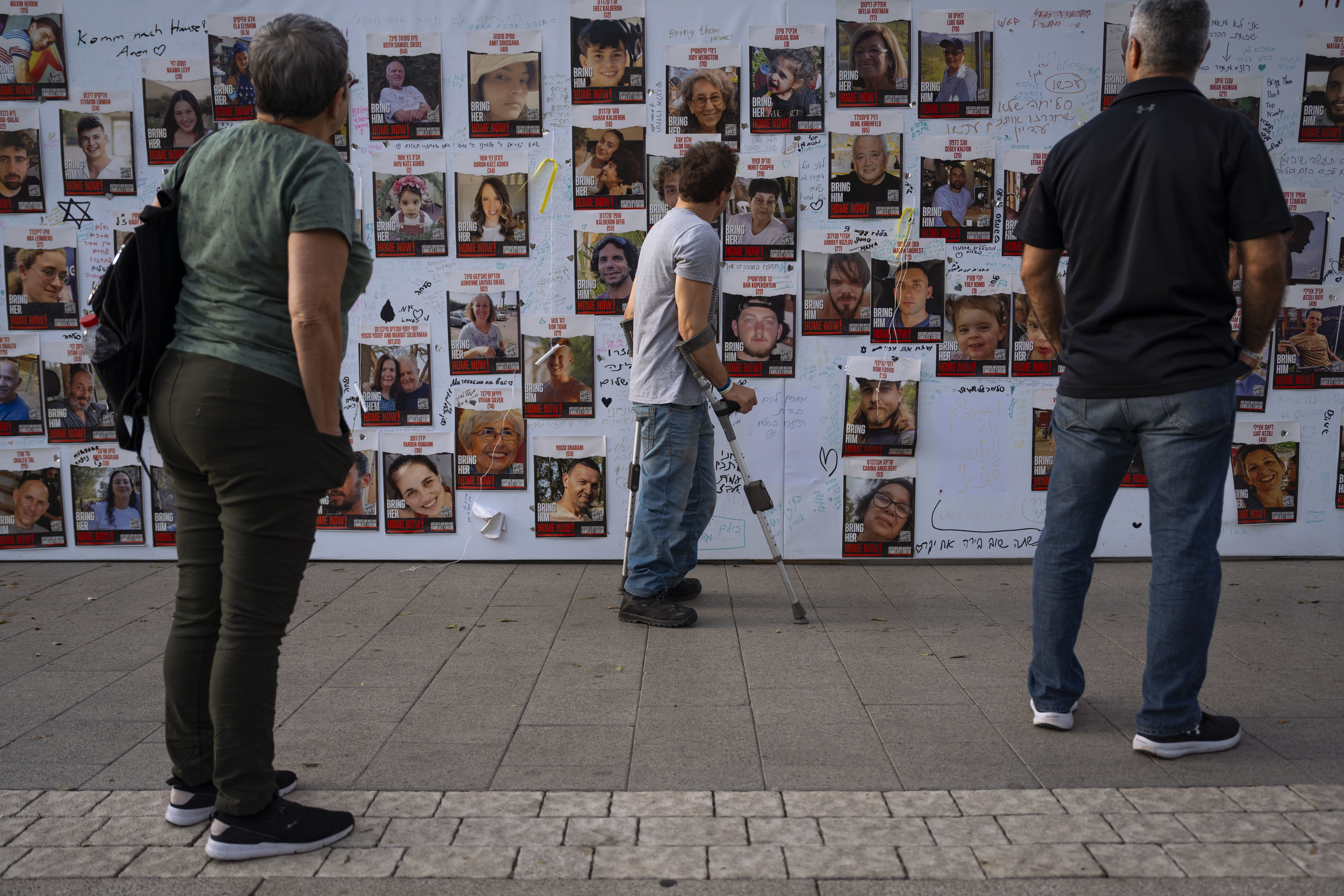 People look at photographs of hostages. mostly Israeli civilians who were abducted during the Oct. 7, unprecedented Hamas attack on Israel, in Tel Aviv, Israel Monday.