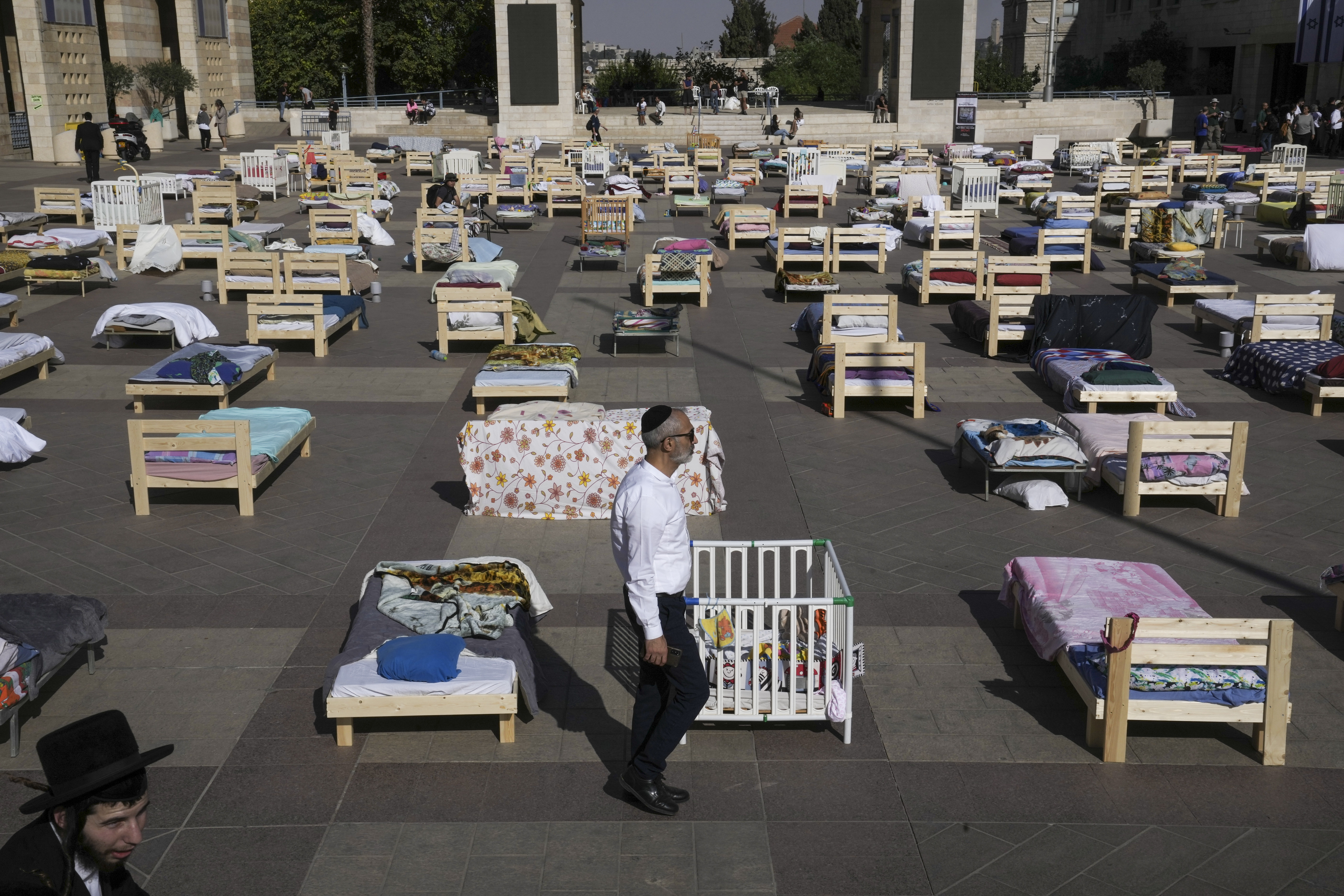 People look at more than 220 beds and items on display symbolizing those captured in a cross-border attack by Hamas militants earlier this month, in Jerusalem, Monday. On Oct. 7, more than 1,400 people, mostly Israeli civilians, were killed and some 240 captured in the unprecedented attack by Hamas, which triggered an ongoing war.
