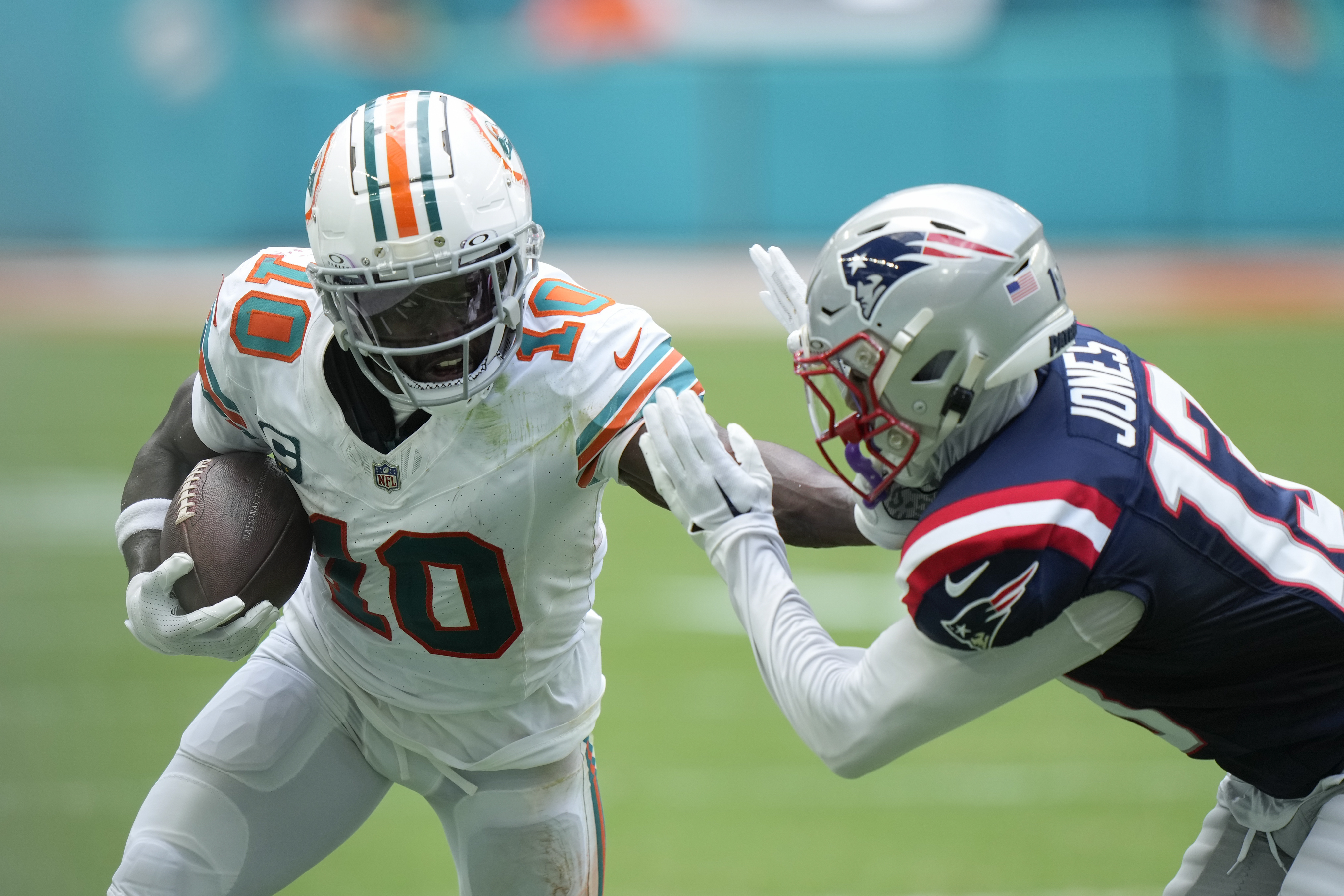 Miami Dolphins wide receiver Tyreek Hill (10) holds off New England Patriots cornerback Jack Jones (13) during the first half of an NFL football game, Sunday, Oct. 29, 2023, in Miami Gardens, Fla.