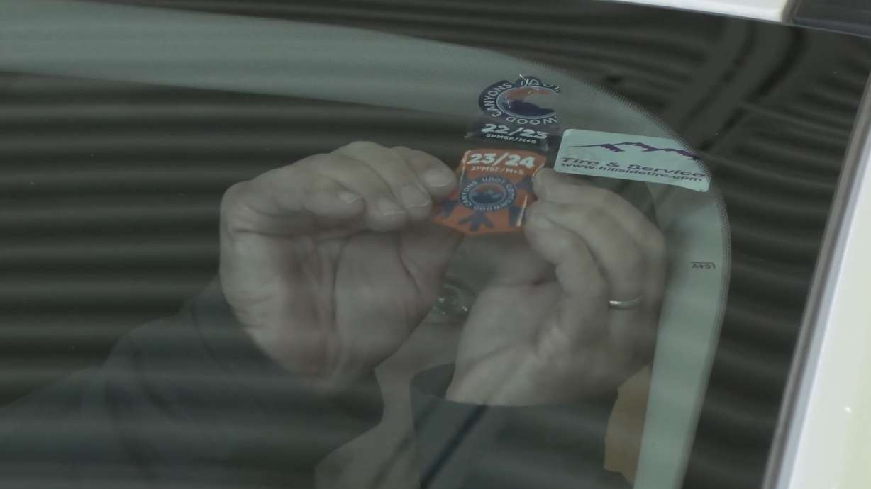 A driver places a Cottonwood Canyons Sticker Program sticker onto their car after it passed an inspection Wednesday morning. This year's program will run through Feb. 28, 2024.
