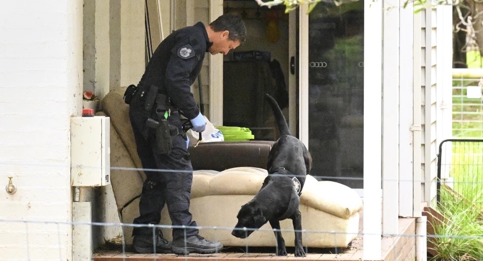 A police officer and dog investigate at the property of Erin Patterson in Leongatha, Australia, Thursday. Australian police have on Thursday arrested Patterson in an investigation of a suspected mushroom poisoning incident.