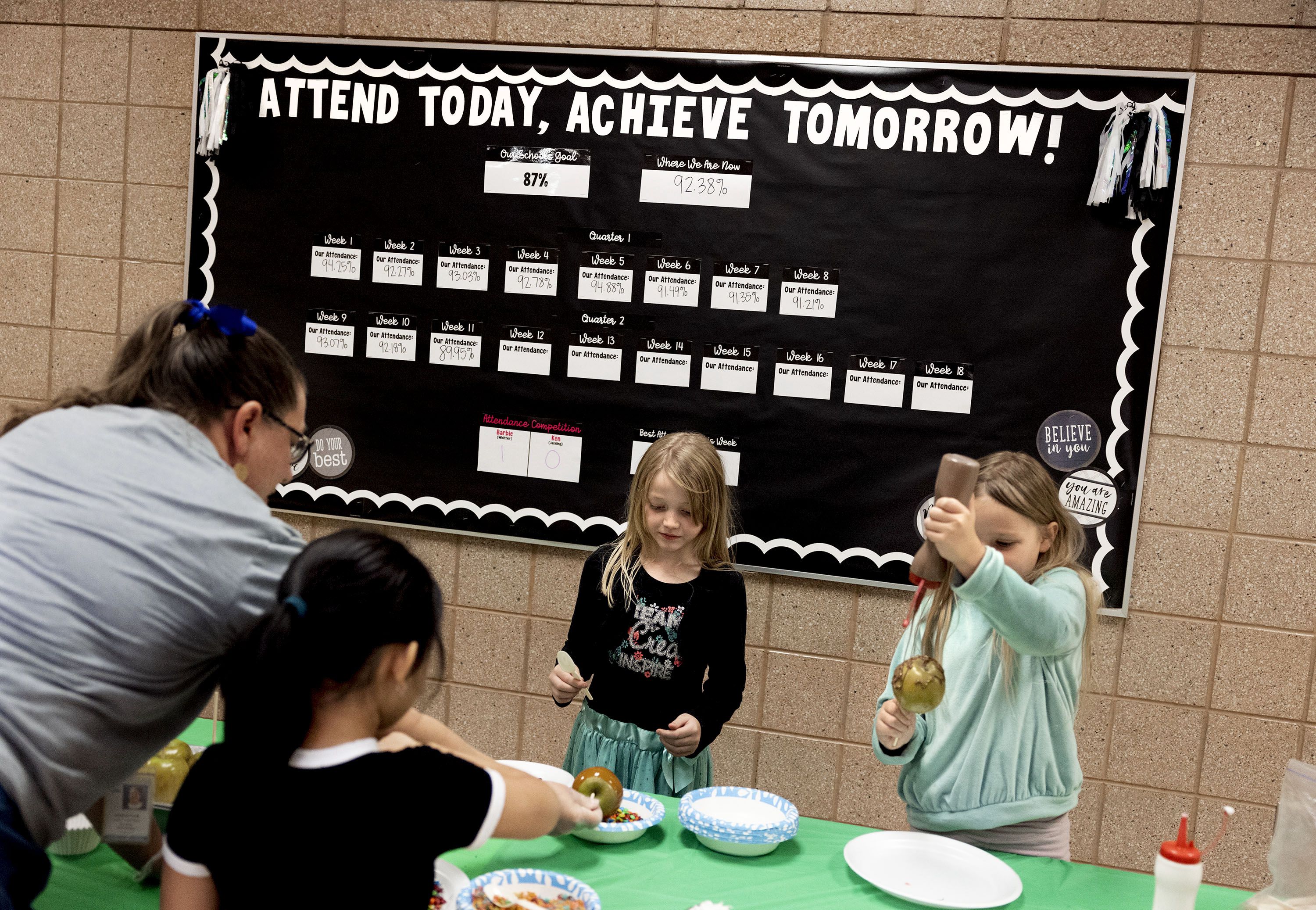 Heather Lane helps Masina Irons, Jazzmyn Brems and Leda Meek make candy apples that they earned for improving their attendance at Whittier Elementary School in West Valley City on Friday. A report shows nearly one-quarter of Utah students are chronically absent. 