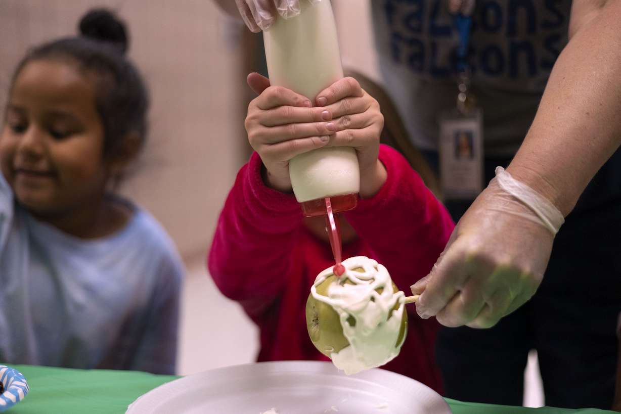 Jill Brems adds white chocolate to an apple at Whittier Elementary School in West Valley on Friday. Brems earned the opportunity to participate in the activity by improving her attendance.