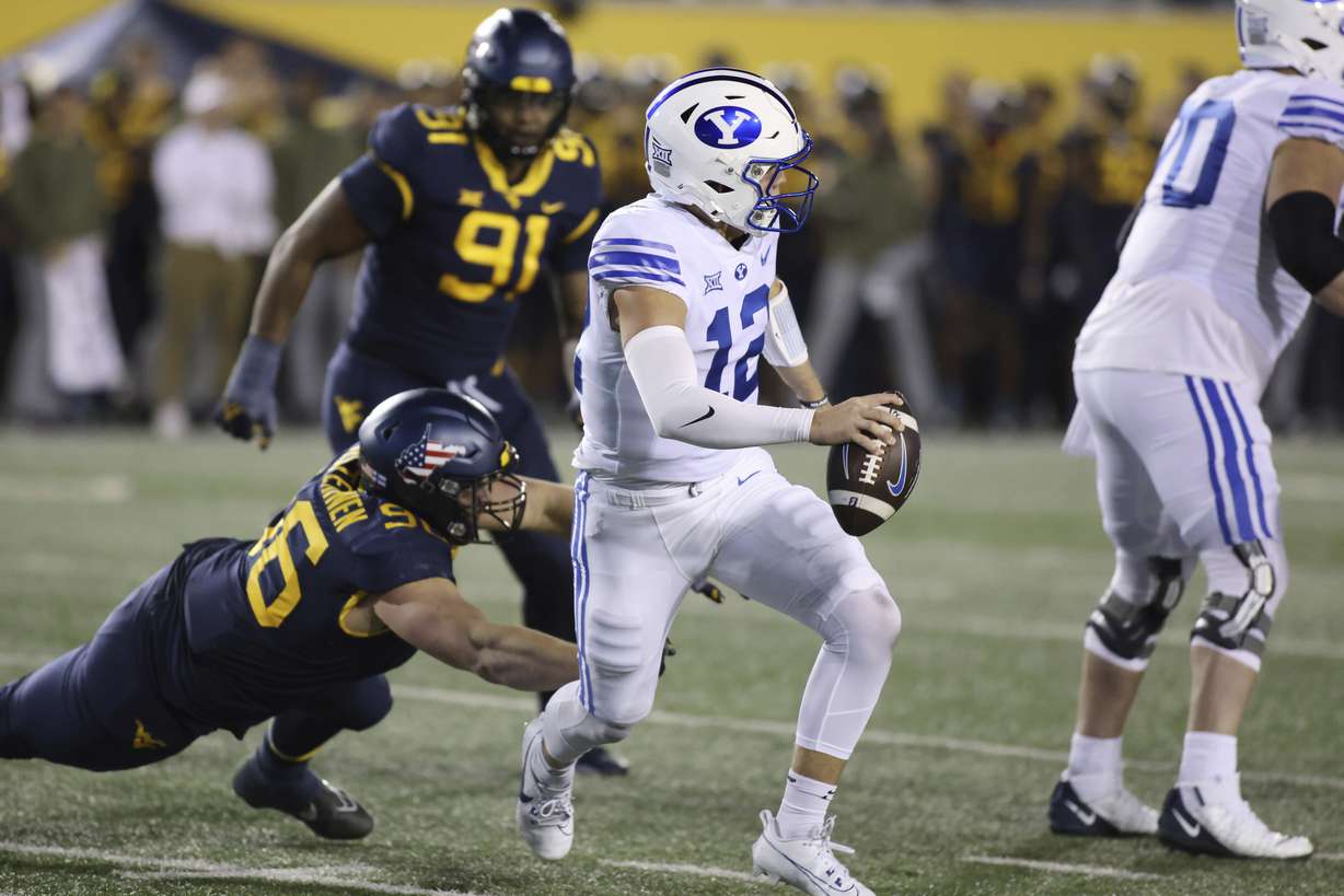 BYU quarterback Jake Retzlaff (12) is rushed out by West Virginia's Edward Vesterinen (96) during the first half of an NCAA college football game on Saturday, Nov. 4, 2023, in Morgantown, W.Va.