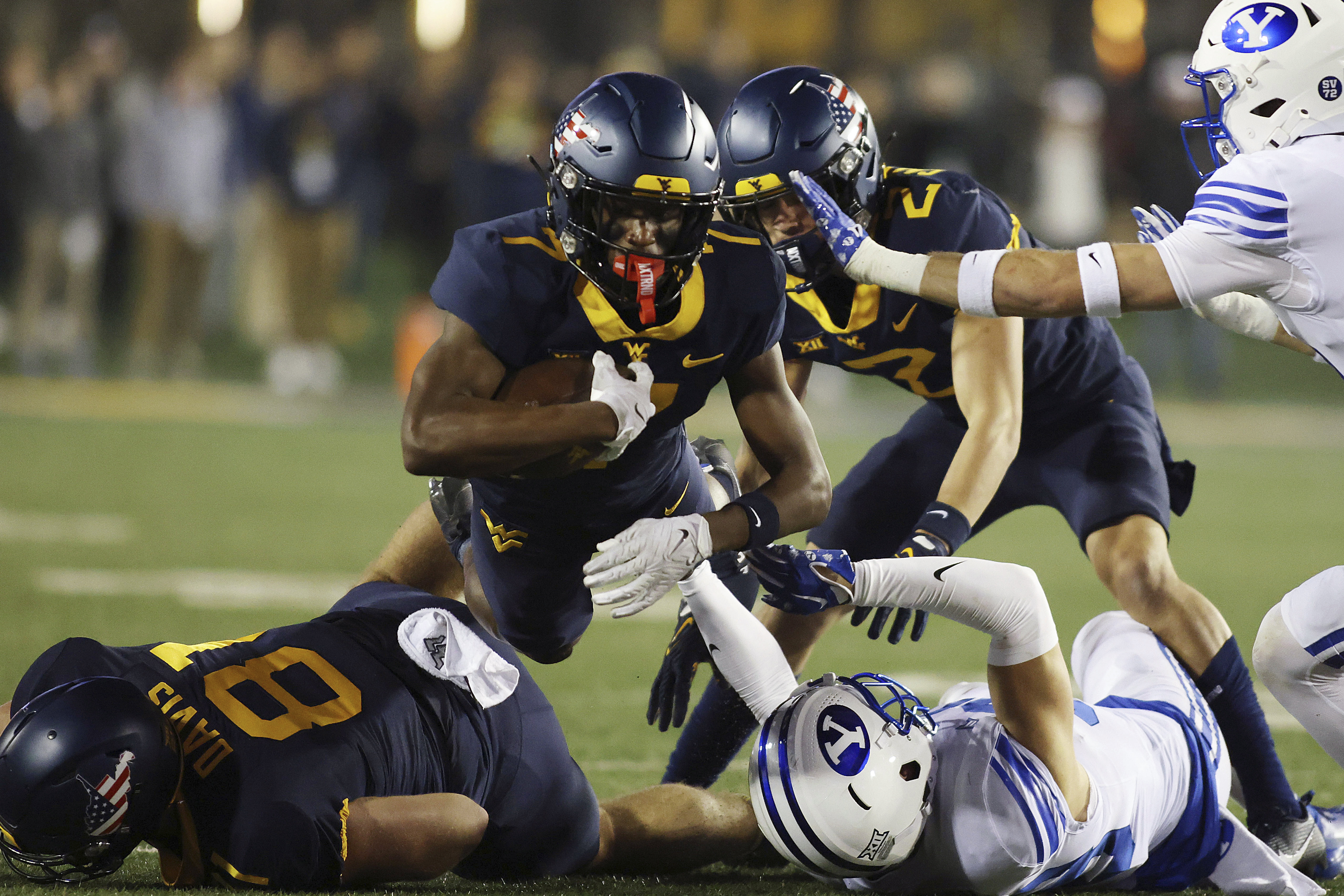 West Virginia's Traylon Ray, top, jumps over players during the first half of an NCAA college football game against BYU on Saturday, Nov. 4, 2023, in Morgantown, W.Va. 