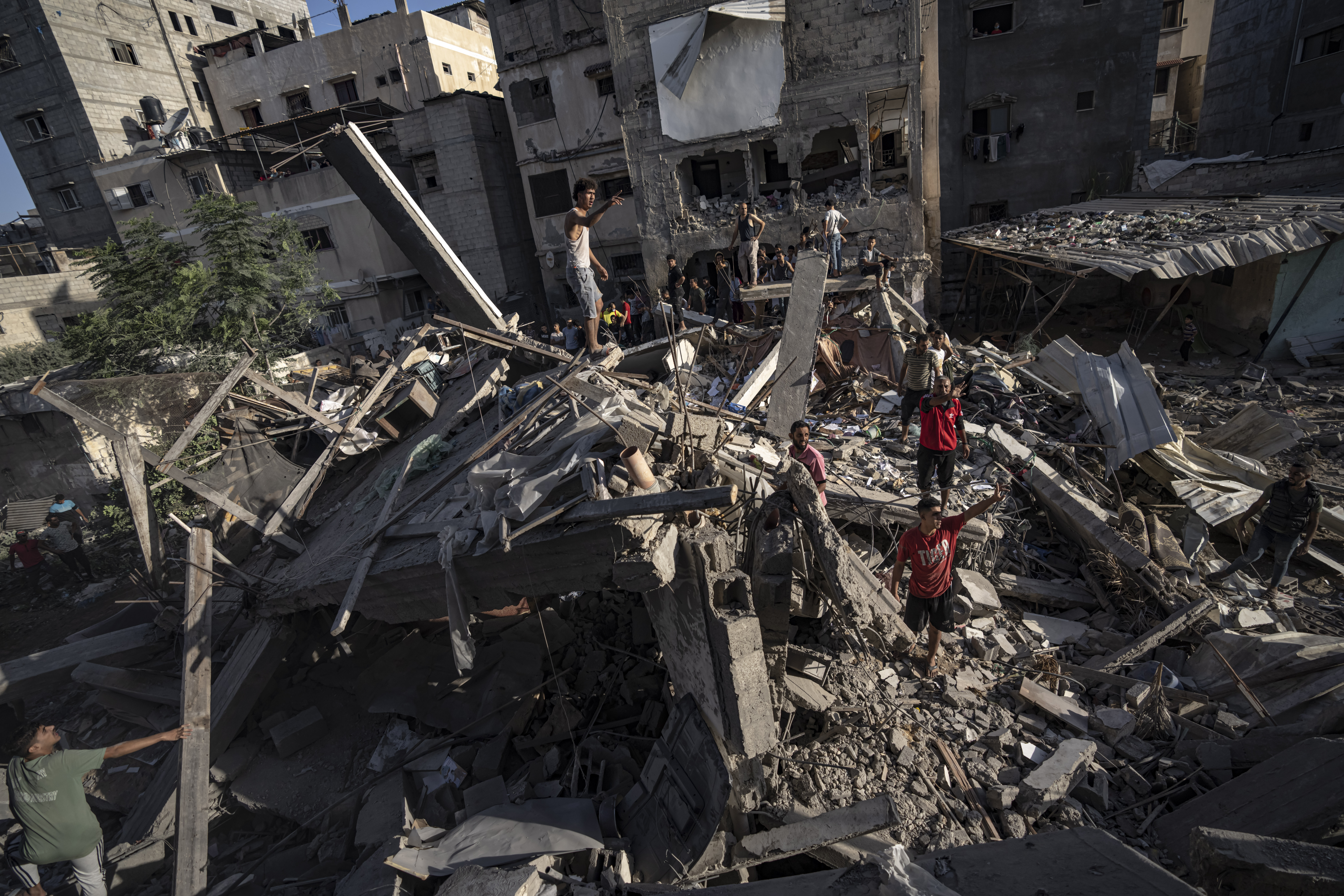 Palestinians look at the destruction after Israeli strikes on the Gaza Strip in Khan Younis, Saturday. Israel's military says it has encircled a city in the Gaza Strip and divided the besieged coastal strip into two.