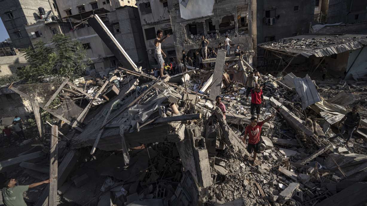 Palestinians look at the destruction after Israeli strikes on the Gaza Strip in Khan Younis, Saturday. Israel's military says it has encircled a city in the Gaza Strip and divided the besieged coastal strip into two.