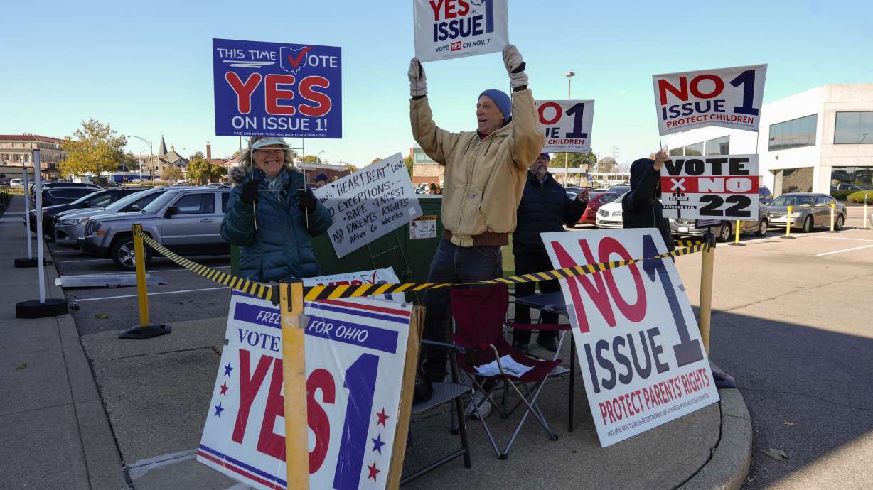 People gather in the parking lot of the Hamilton County Board of Elections as people arrive for early in-person voting in Cincinnati, Thursday. They urge a vote for or against the measure known as Issue 1, the only abortion question on any state ballot this year.