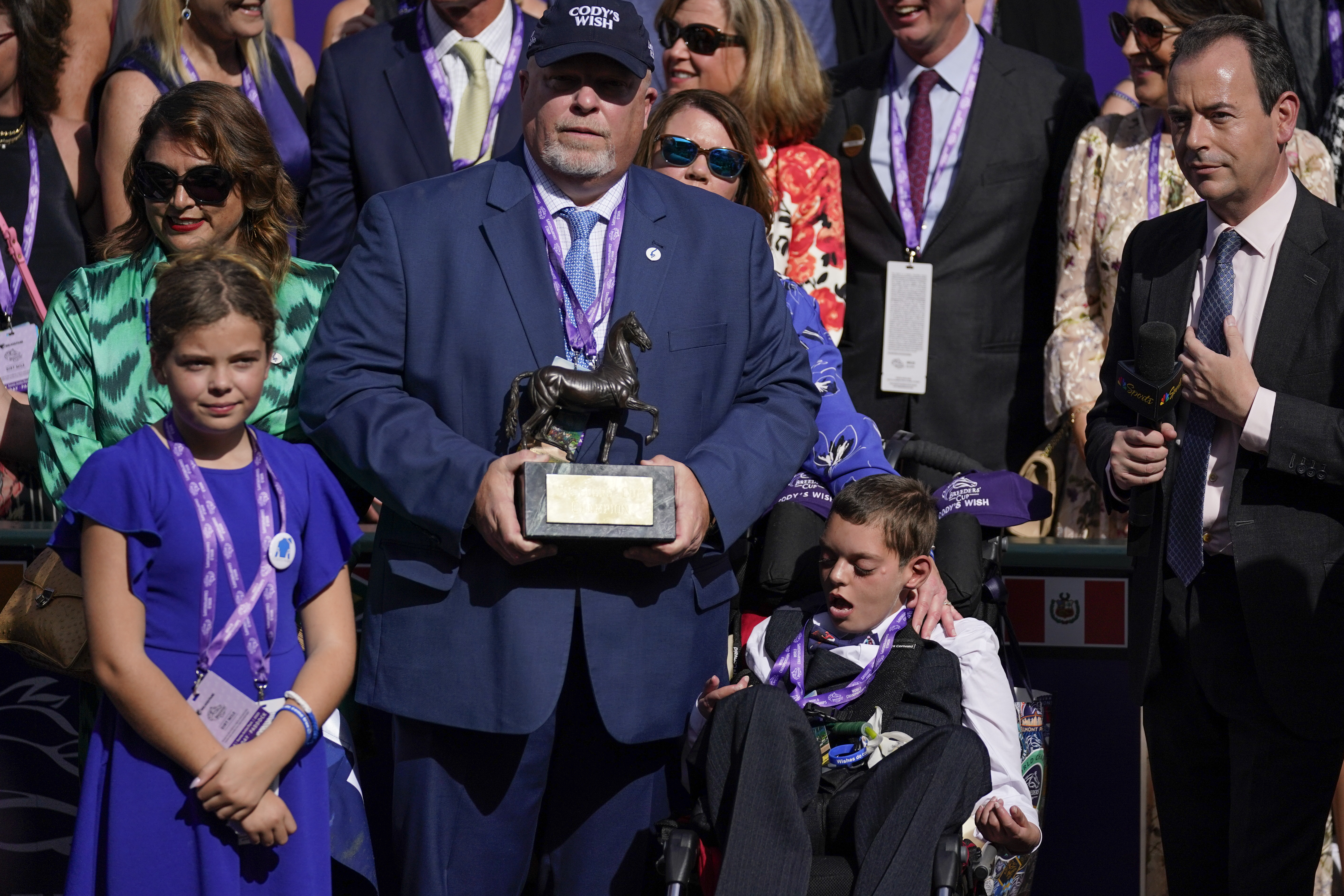 Cody Dorman, center below right, sits alongside his father Kelly Dorman, left holding trophy, mother Leslie Dorman, second from left, behind, and sister Kylie, left, after jockey Junior Alvarado rode Cody's Wish to win the Breeders' Cup Dirt Mile horse race Saturday, Nov. 4, 2023, at Santa Anita Park in Arcadia, Calif. Cody's Wish is named after Cody Dorman.