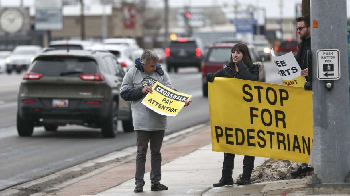 Shane Siwik and Corey Thomas hold signs for a honk and wave at 3300 South and West Temple as they try to draw attention to pedestrian safety on March 22, 2019. A safety advocacy group is now pushing to ban turning right on a red light.