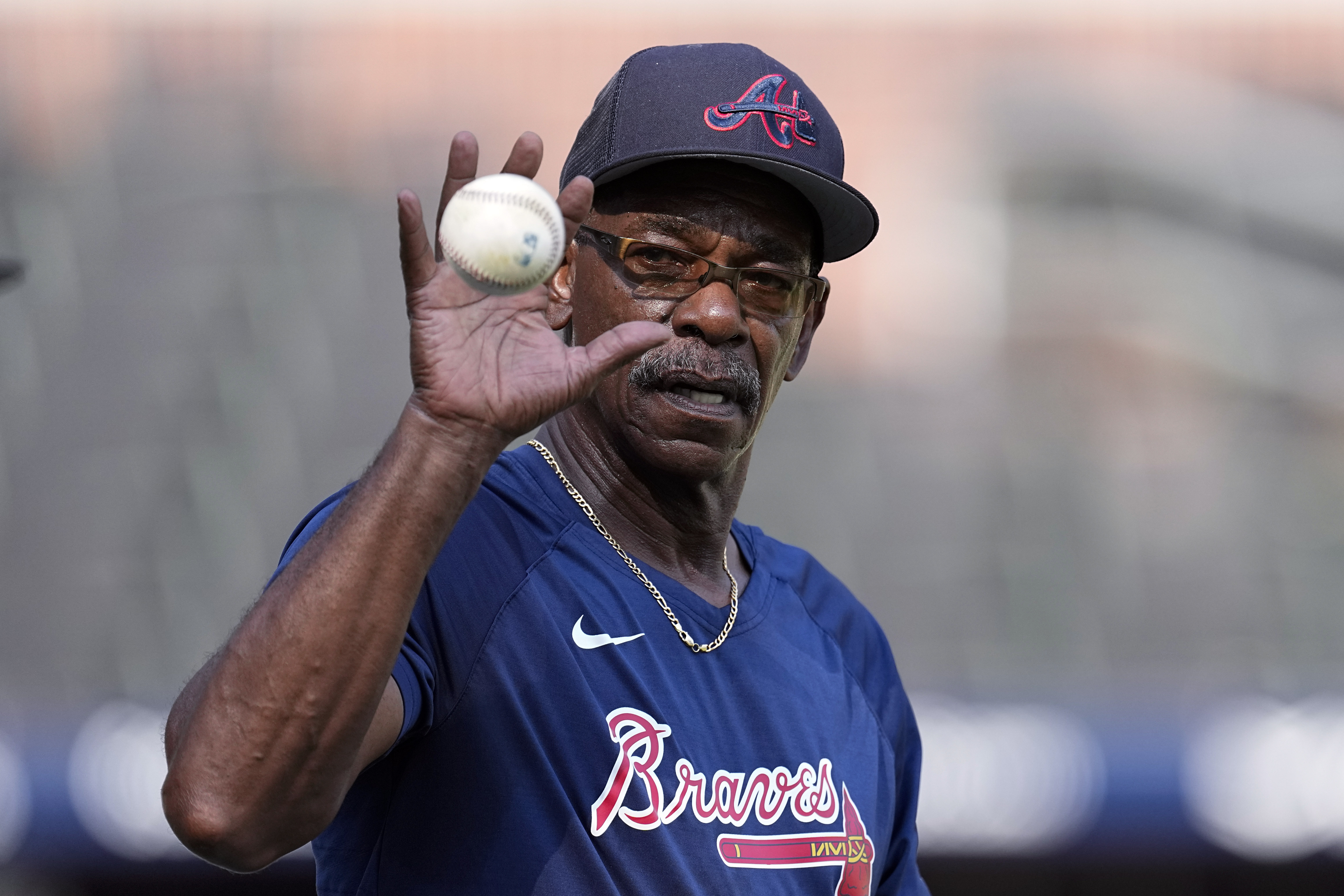 FILE - Atlanta Braves third base coach Ron Washington (37) reaches for a ball before a baseball game against the New York Mets Monday, Aug. 21, 2023, in Atlanta. The Los Angeles Angels have hired Washington to be their new manager. The 71-year-old Washington managed the Texas Rangers from 2007-14, winning two AL pennants and going 664–611. He spent the past seven seasons as Atlanta’s third base coach, helping the Braves to their 2021 World Series title.