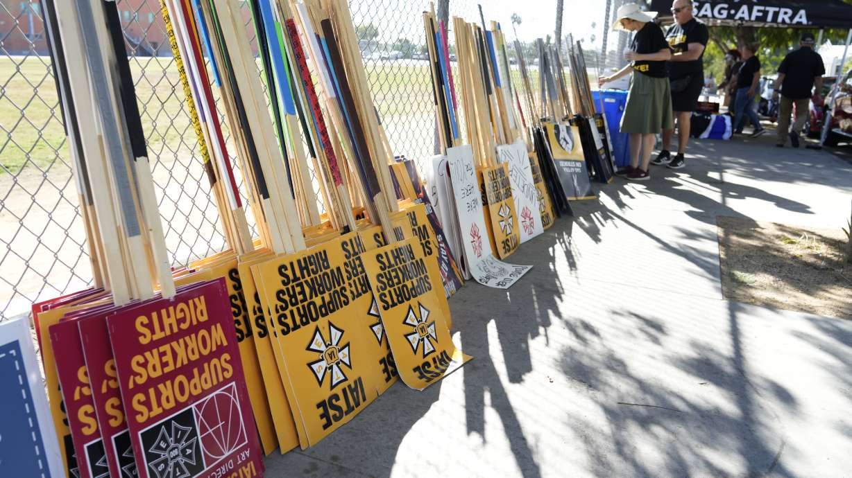 Striking SAG-AFTRA members pick out signs for a picket line outside Netflix studios, Wednesday in Los Angeles.