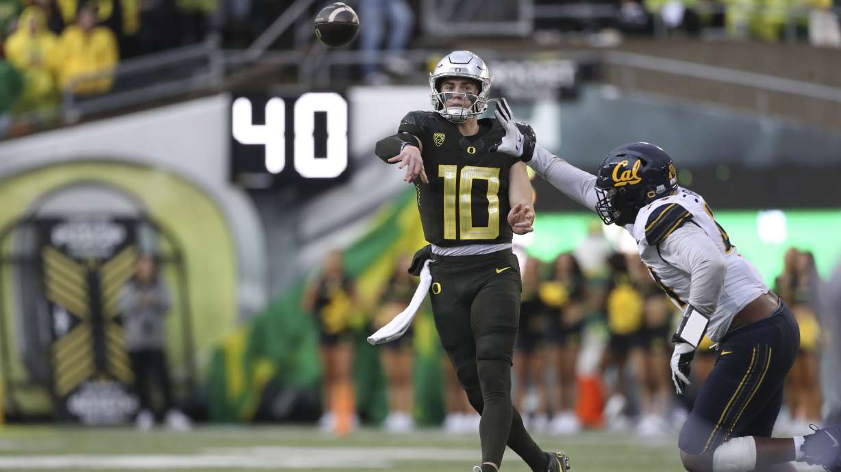 Oregon quarterback Bo Nix (10) throws a pass as California linebacker Xavier Carlton, right, defends during the first half of an NCAA football game, Saturday, Nov. 4, 2023, in Eugene, Ore.