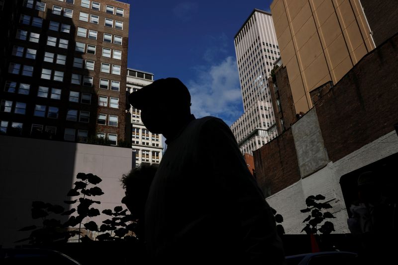 A man is seen silhouetted, walking near the financial district of New York City on Oct. 18, 2021. Moody's on Friday lowered its outlook on the U.S. credit rating to "negative" from "stable."