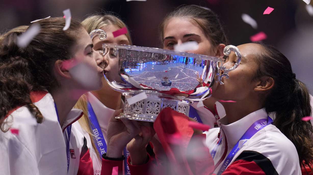 Canada's Leylah Fernandez, right, kisses the trophy with members of her team after wining the final singles tennis match against Italy's Jasmine Paolini, during the Billie Jean King Cup finals in La Cartuja stadium in Seville, southern Spain, Spain, Sunday, Nov. 12, 2023.