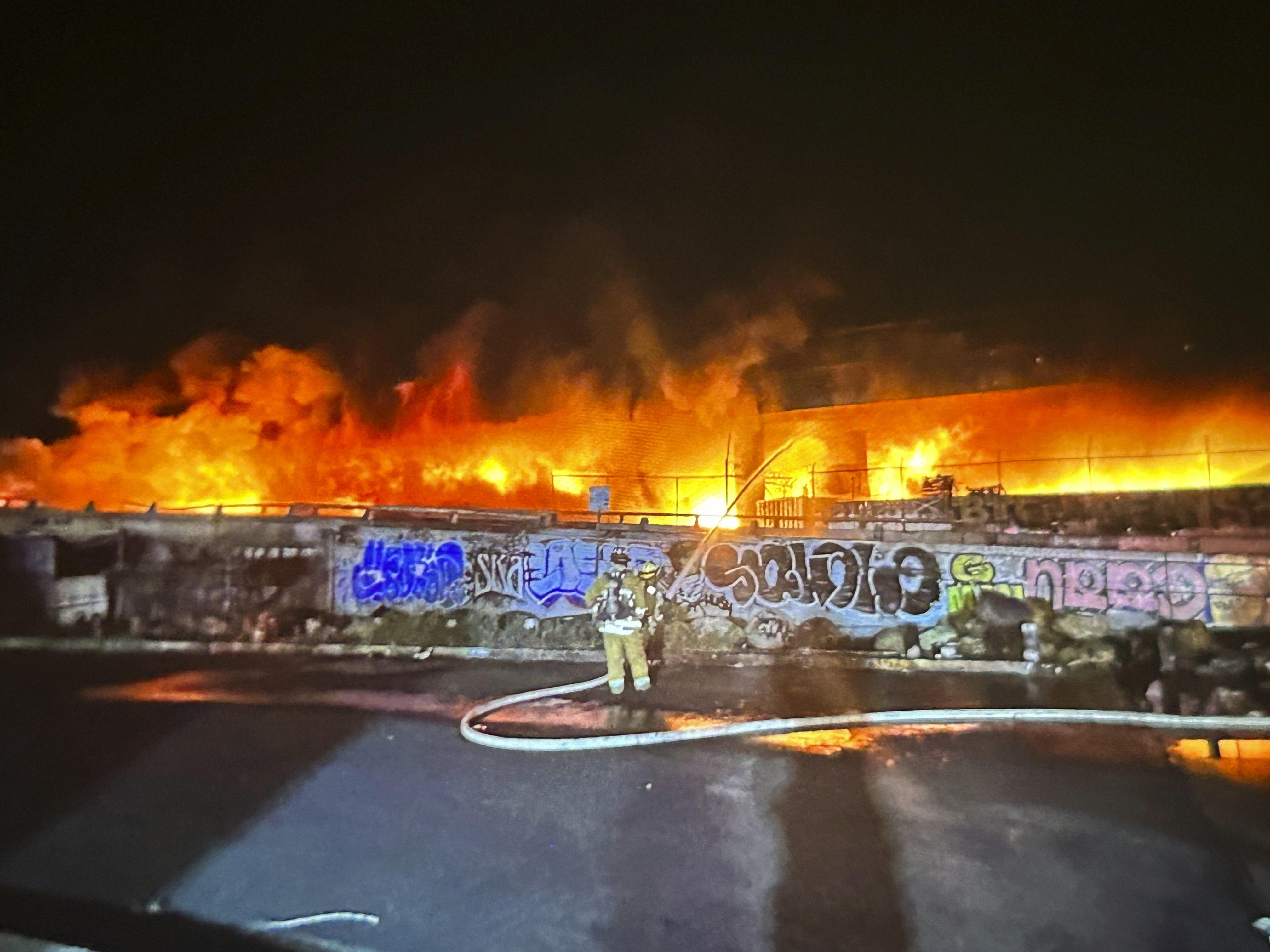 An early morning fire along Interstate 10 near downtown Los Angeles burns Saturday. Gov. Gavin Newsom says damage caused by the act of arson can be repaired in three to five weeks.