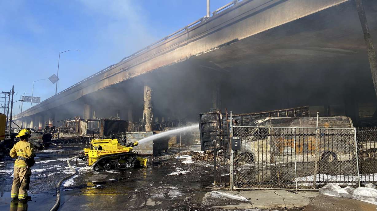 A Los Angeles firefighter uses a robotic hose to douse a fire under Interstate 10 that severely damaged the overpass in an industrial zone near downtown Los Angeles, Saturday.