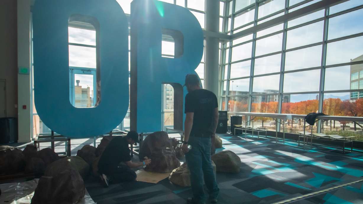 Crews work to paint makeshift rocks by an Outdoor Retailer sign inside the Salt Palace Convention Center in Salt Lake City on Monday. Its Winter Show runs from Tuesday through Thursday.