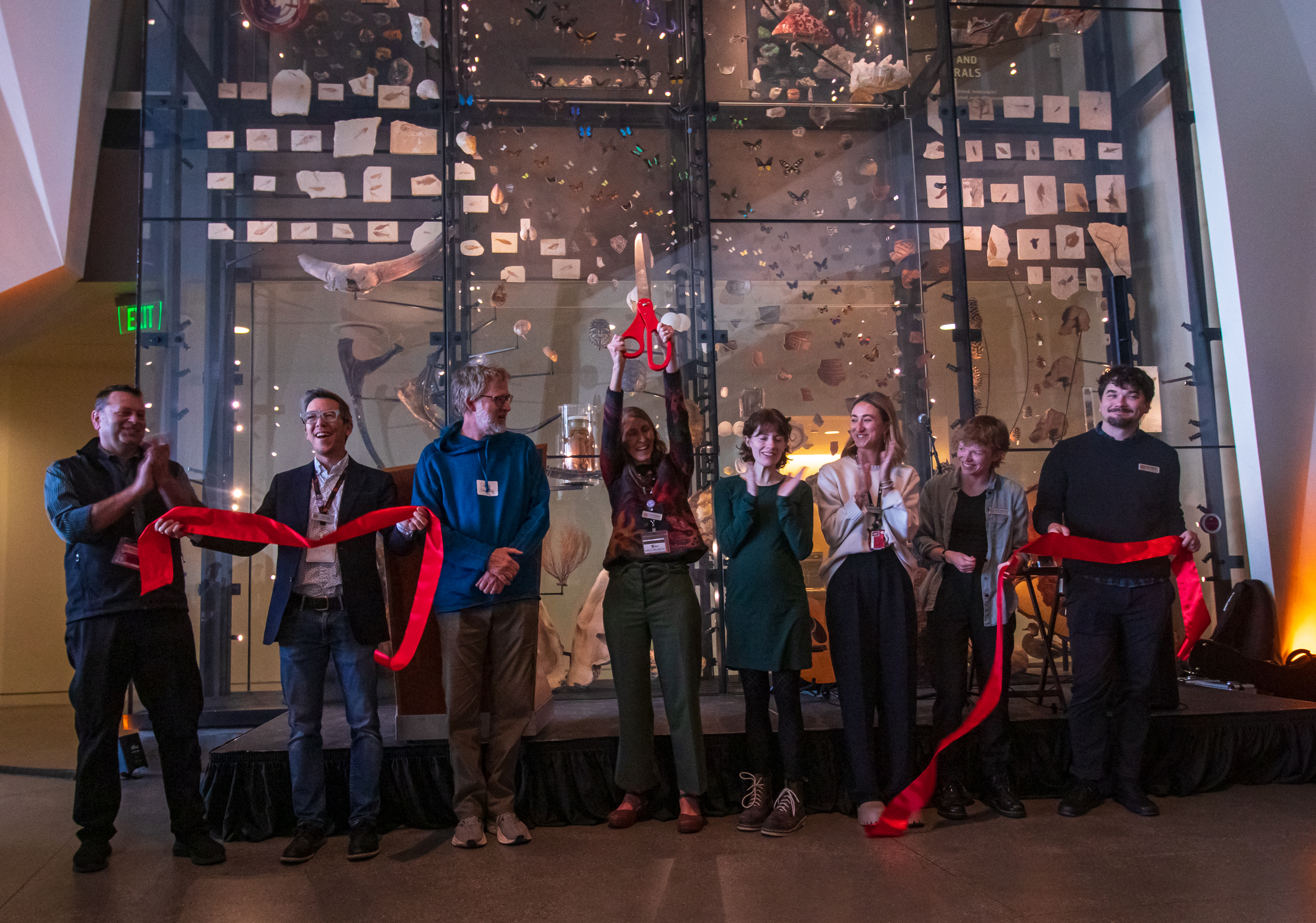 Lisa Thompson, senior exhibit developer for the Natural History Museum of Utah, holds up a giant pair of scissors while other museum officials and project dignitaries applaud the opening of "A Climate of Hope" Saturday morning. It's the museum's first new permanent exhibit in 12 years.
