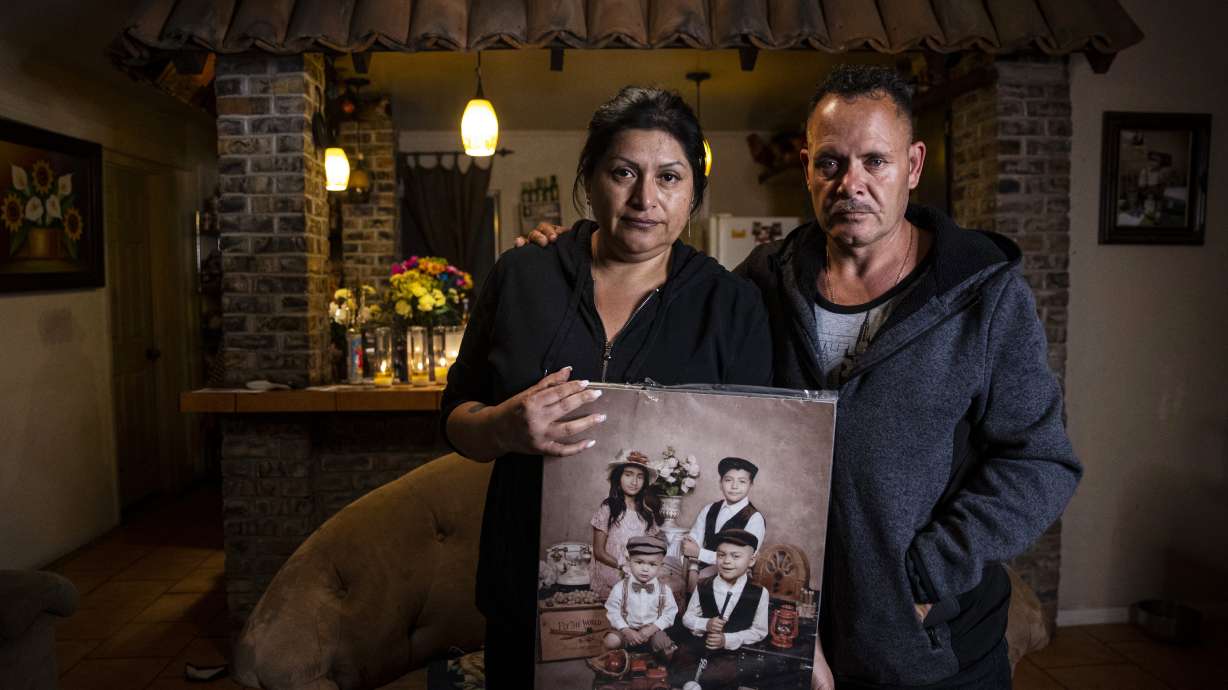 Erlinda Zacarias, left, and her husband, Jesus Mejia-Santana, pose for a photo, Jan. 31, 2022, while holding a portrait showing four of their six children who died on Jan. 29, 2022, in a mass-casualty traffic collision in North Las Vegas.