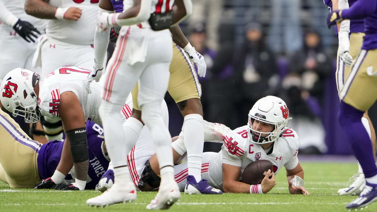 Utah quarterback Bryson Barnes (16) looks up after being tackled by Washington defensive end Bralen Trice (8) during the second half of an NCAA college football game Saturday, Nov. 11, 2023, in Seattle.