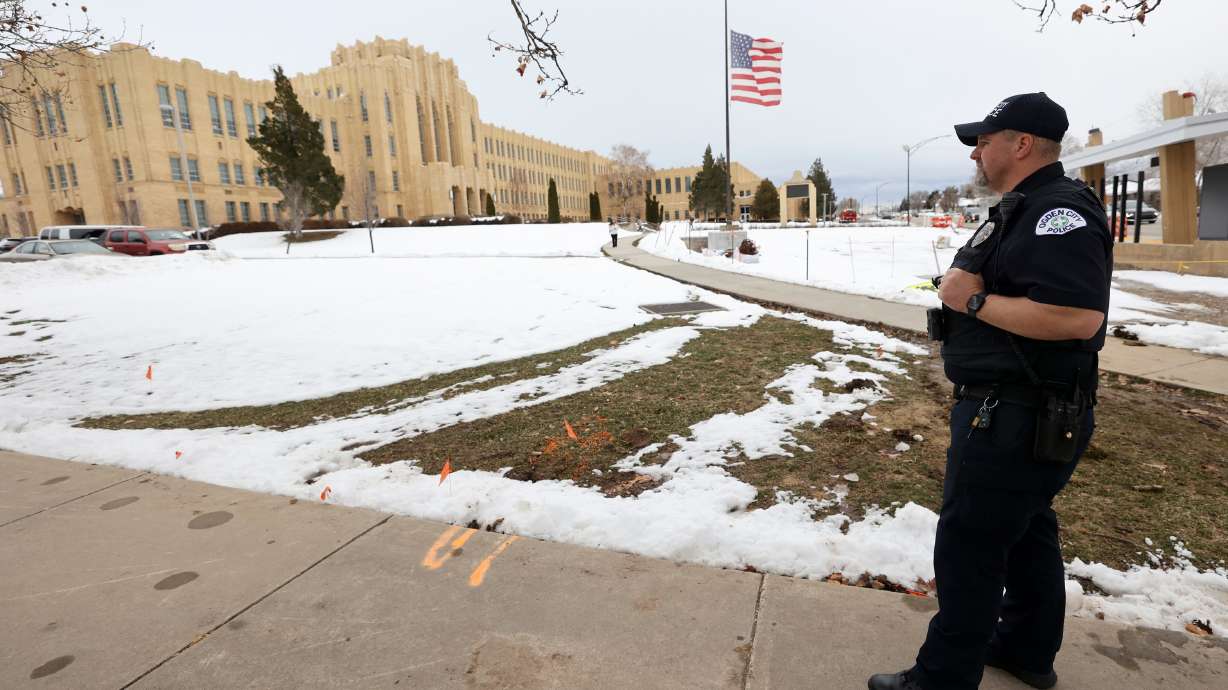 Officer Chavis Whitby stands outside Ogden High School after false threats of shots fired on March 29. A task force Wednesday recommended a bill that would require every Utah school to have an armed employee on campus