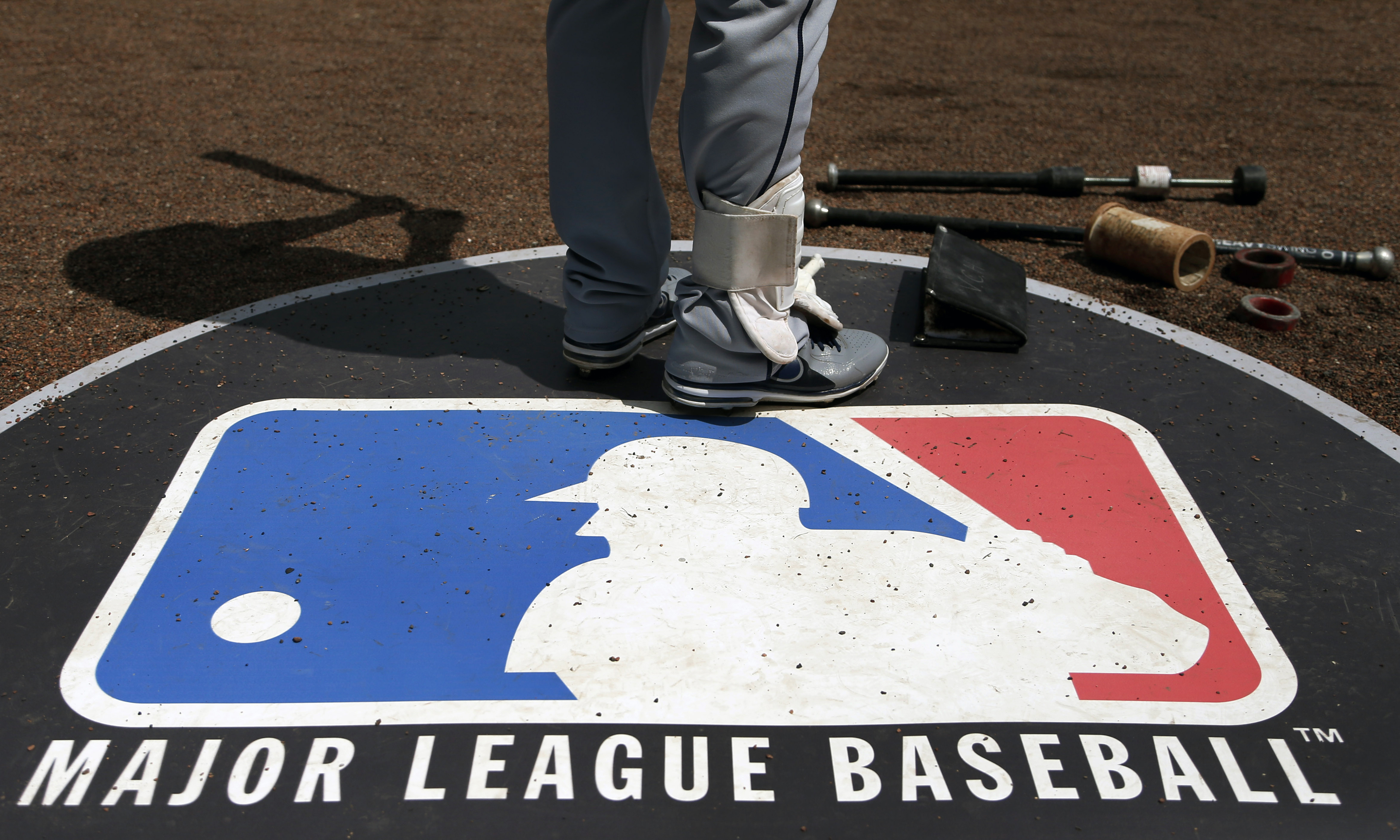 FILE - A baseball player stands on the Major League Baseball, MLB, logo on April 24, 2013, in Chicago. Police say the Detroit Tigers complex in the Dominican Republic was targeted Wednesday, Oct. 18, 2023, in the latest robbery of a Major League Baseball facility in the country. 