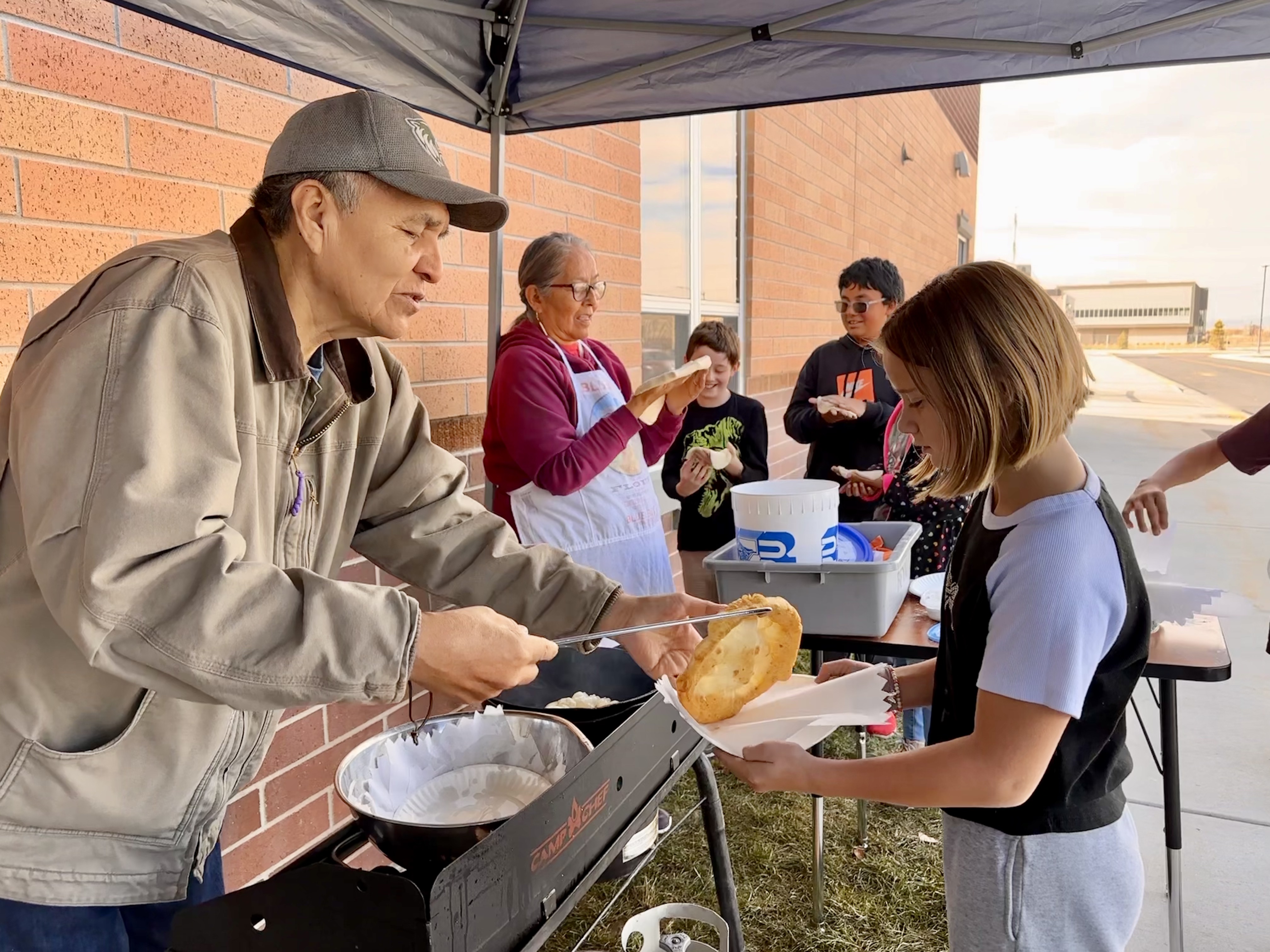 Anthony Beyal hands a hot piece of fry bread to fifth grader Jamison King, 10, at Meadow Brook Elementary School in Springville on Nov. 13 during a lesson from the BYU Arts Partnership's Native American Curriculum Initiative.