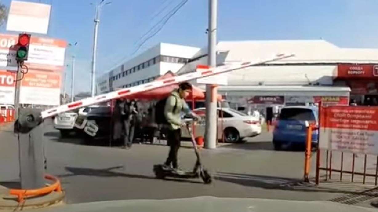 A scooter-rider attempts to get past a gate in this Japanese town. But does he make it?